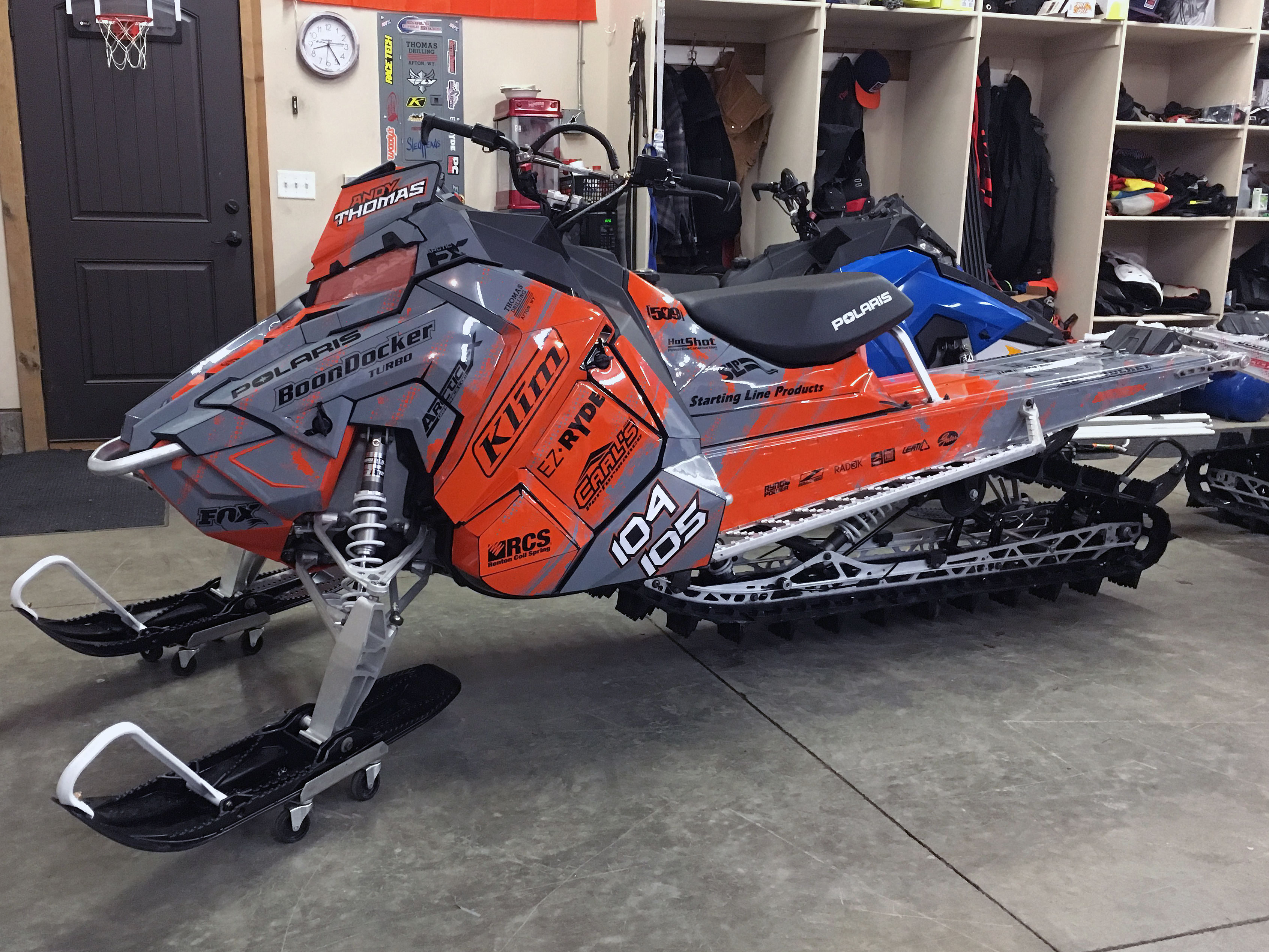 A Polaris Axys Mountain snowmobile with a orange and gray Sabotage custom vinyl wrap.