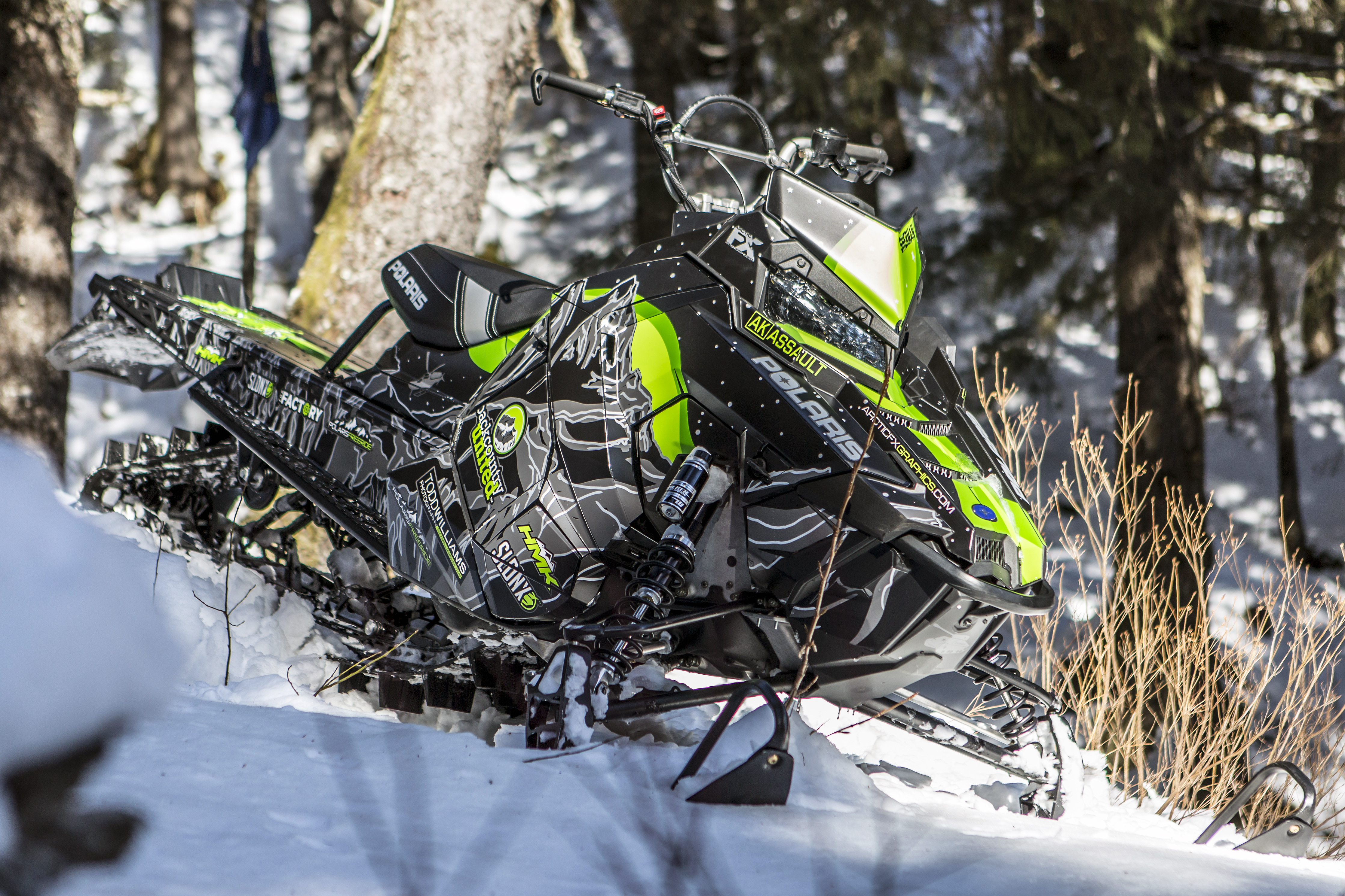 A Polaris Axys Mountain snowmobile with a lime, black, and gray Sherman AK Assault custom vinyl wrap.