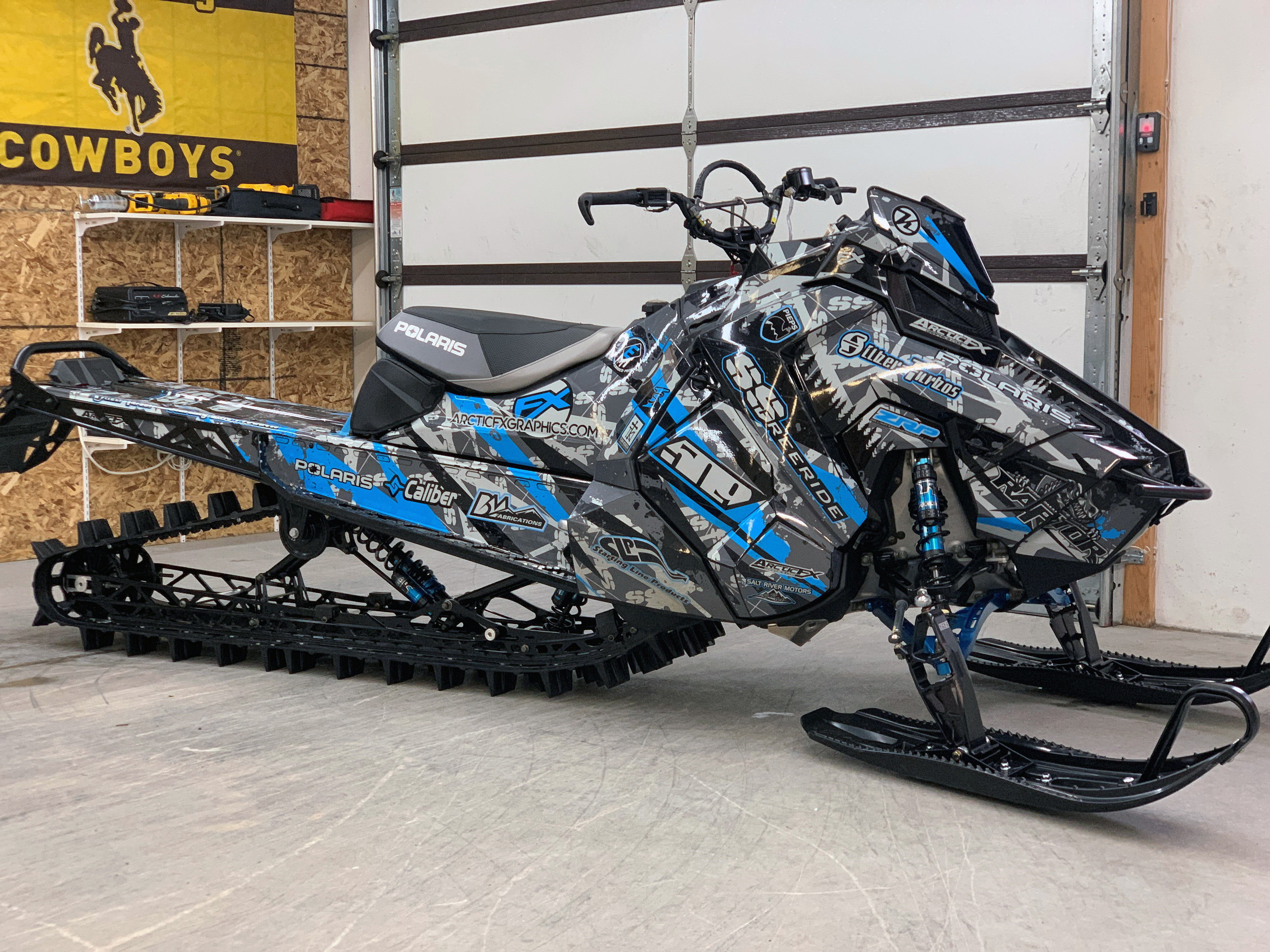 A Polaris Axys Mountain snowmobile with a gray, blue, and black Skinner Aftermath custom vinyl wrap.