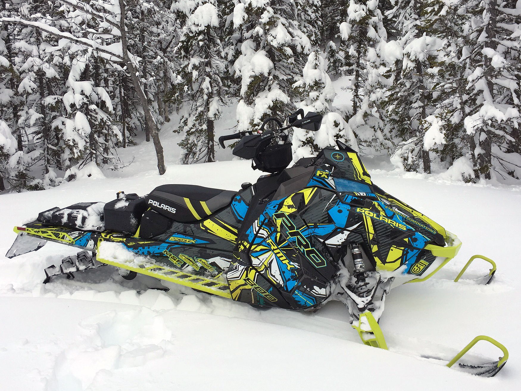 A Polaris Axys Mountain snowmobile with a lime squeeze, gray, and blue Stricken custom vinyl wrap.