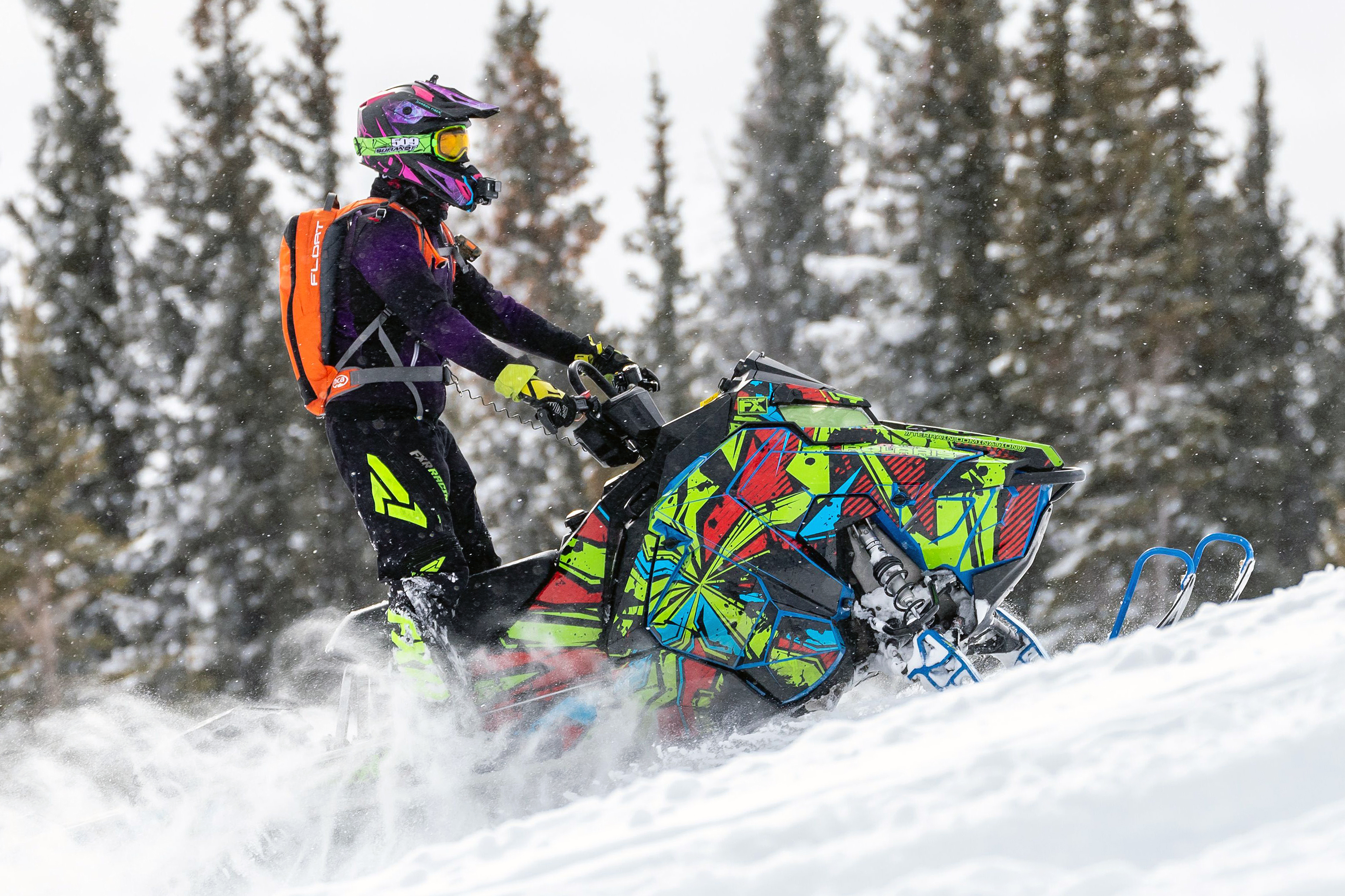 A Polaris Axys Mountain snowmobile with a red, lime, and blue Stricken custom vinyl wrap.