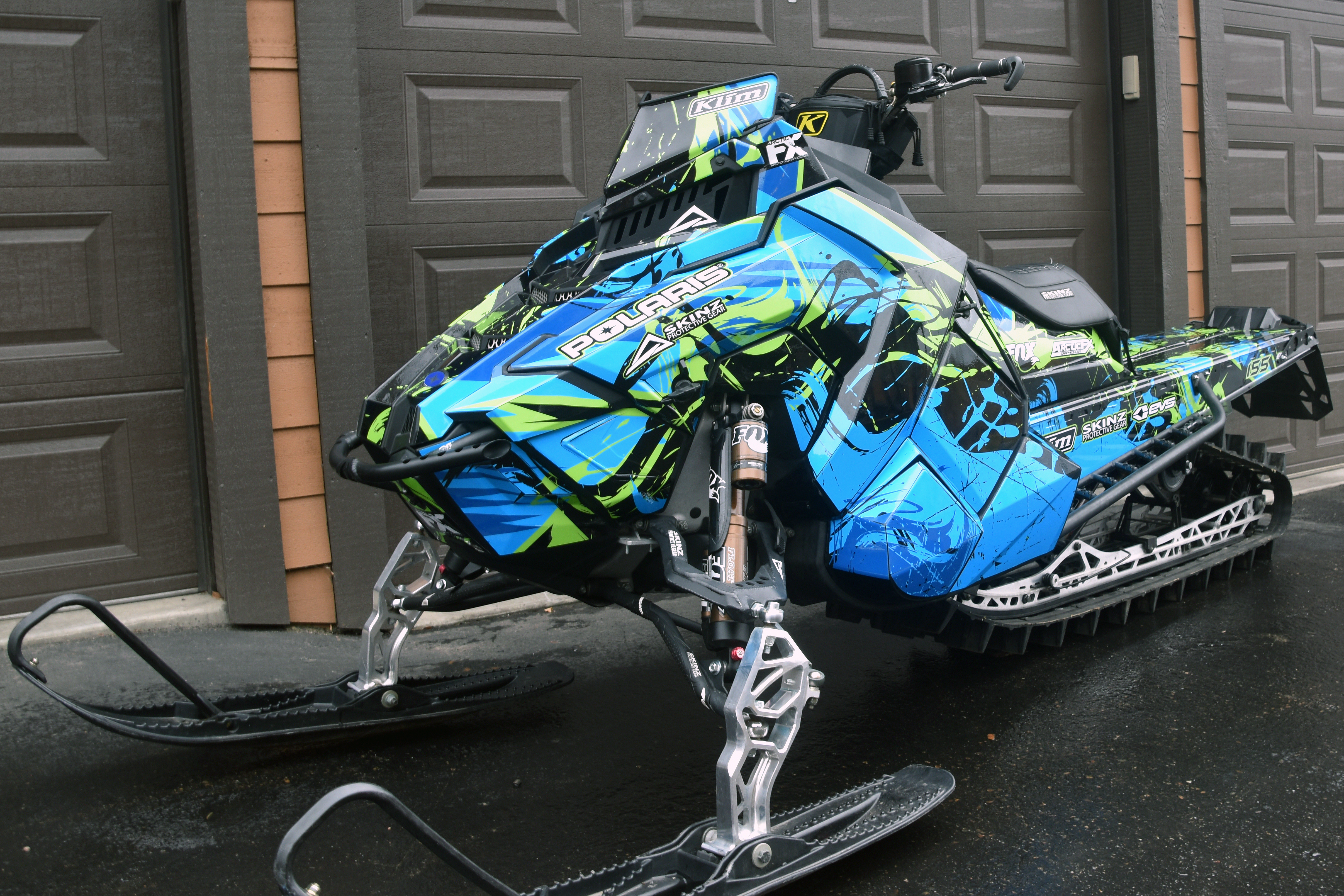 A Polaris Axys Mountain snowmobile with a lime, black, and blue Sub Zero custom vinyl wrap.