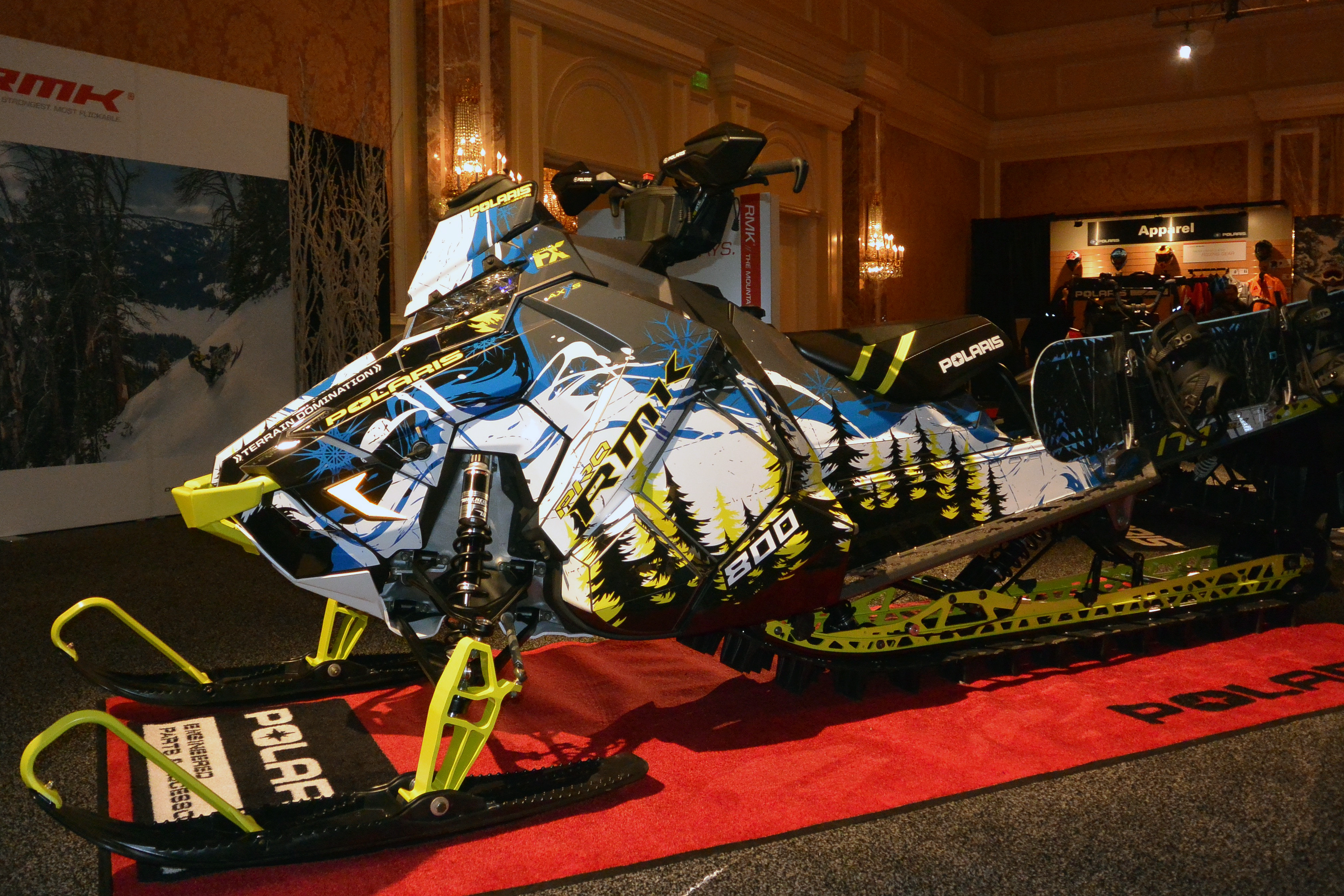 A Polaris Axys Mountain snowmobile with a lime squeeze, black, and blue Sub Zero custom vinyl wrap.