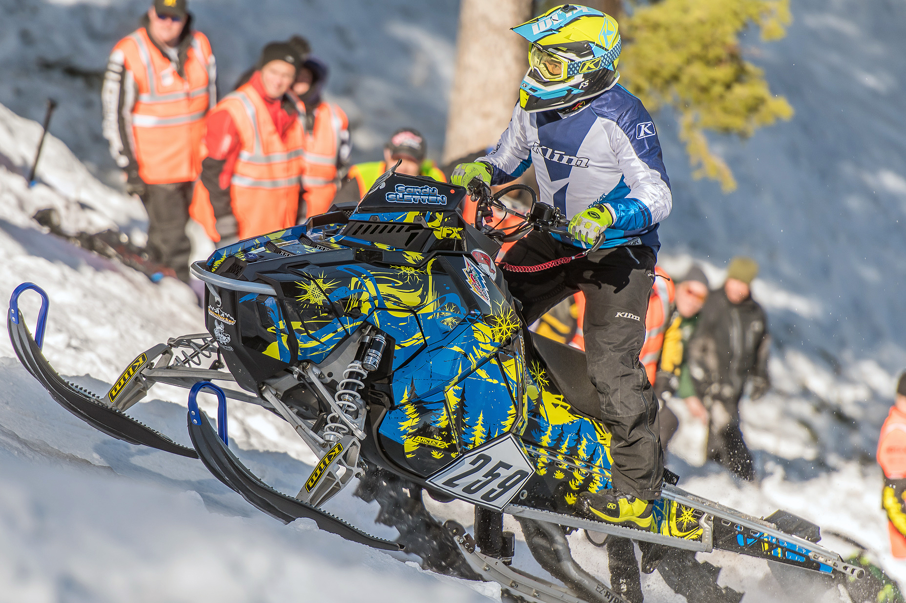 A Polaris Axys Mountain snowmobile with a lime squeeze, black, and blue Sub Zero custom vinyl wrap.