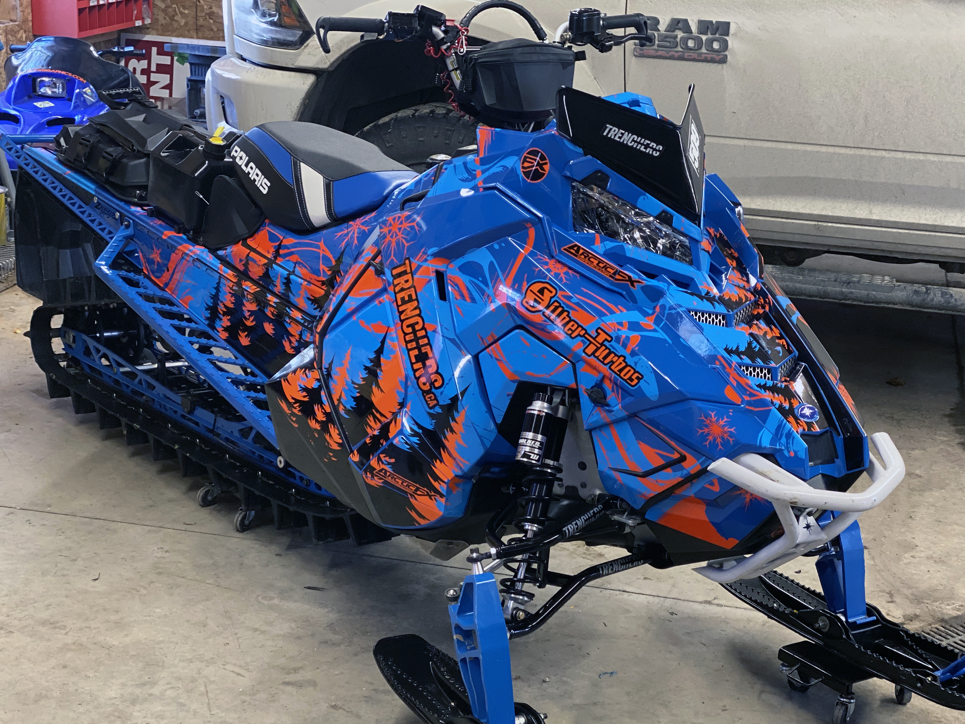A Polaris Axys Mountain snowmobile with a orange, cyan, and blue Sub Zero custom vinyl wrap.