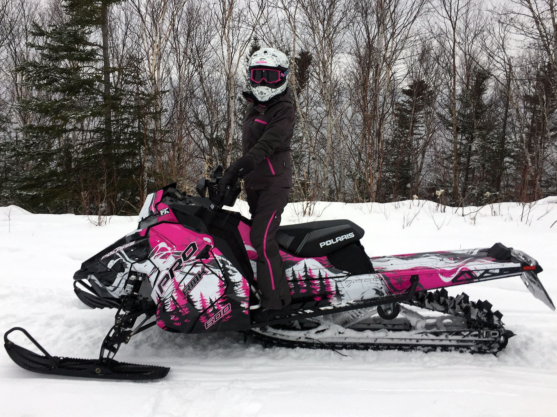 A Polaris Axys Mountain snowmobile with a pink, black, and white Sub Zero custom vinyl wrap.