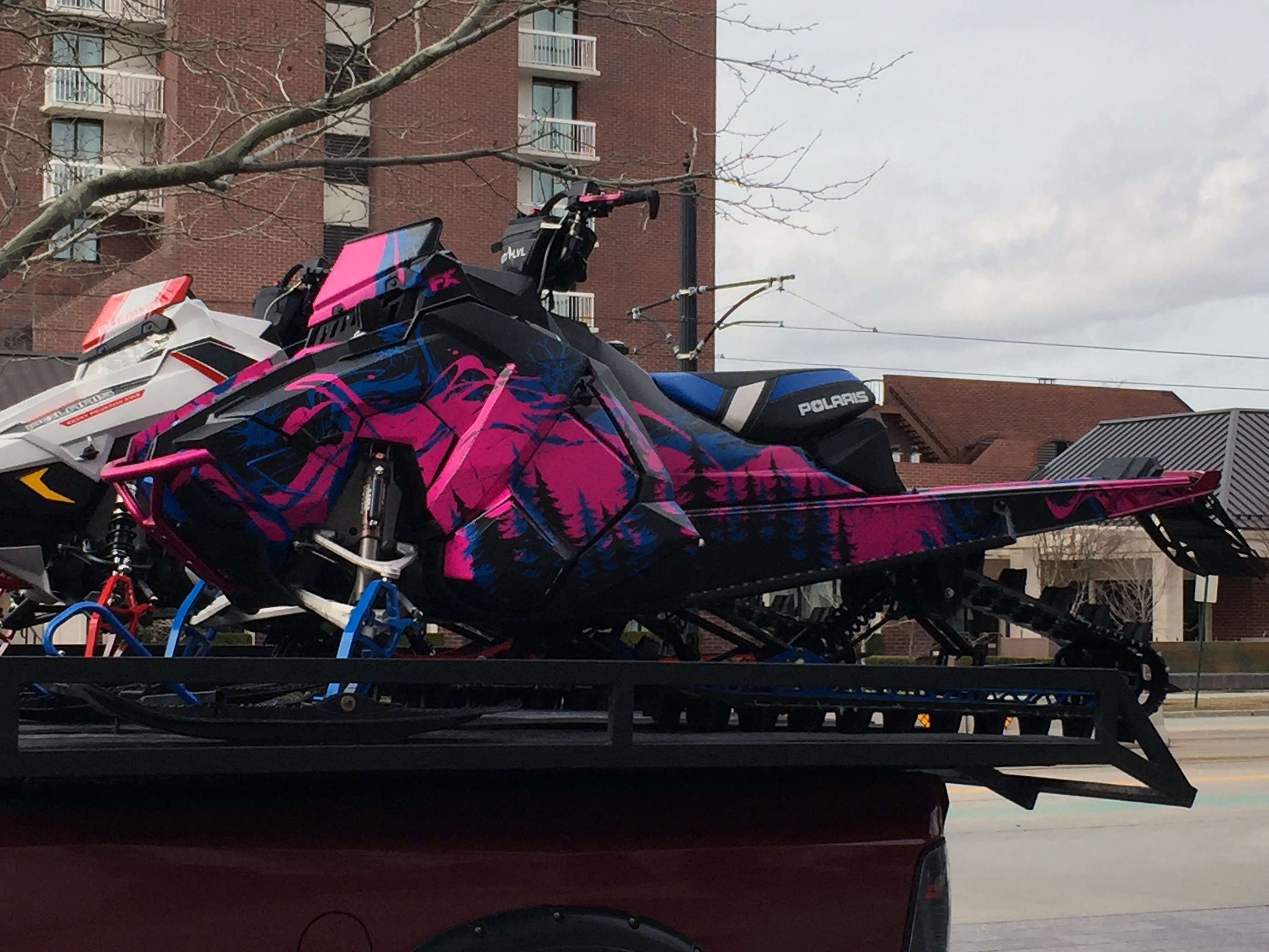 A Polaris Axys Mountain snowmobile with a pink, blue, and black Sub Zero custom vinyl wrap.