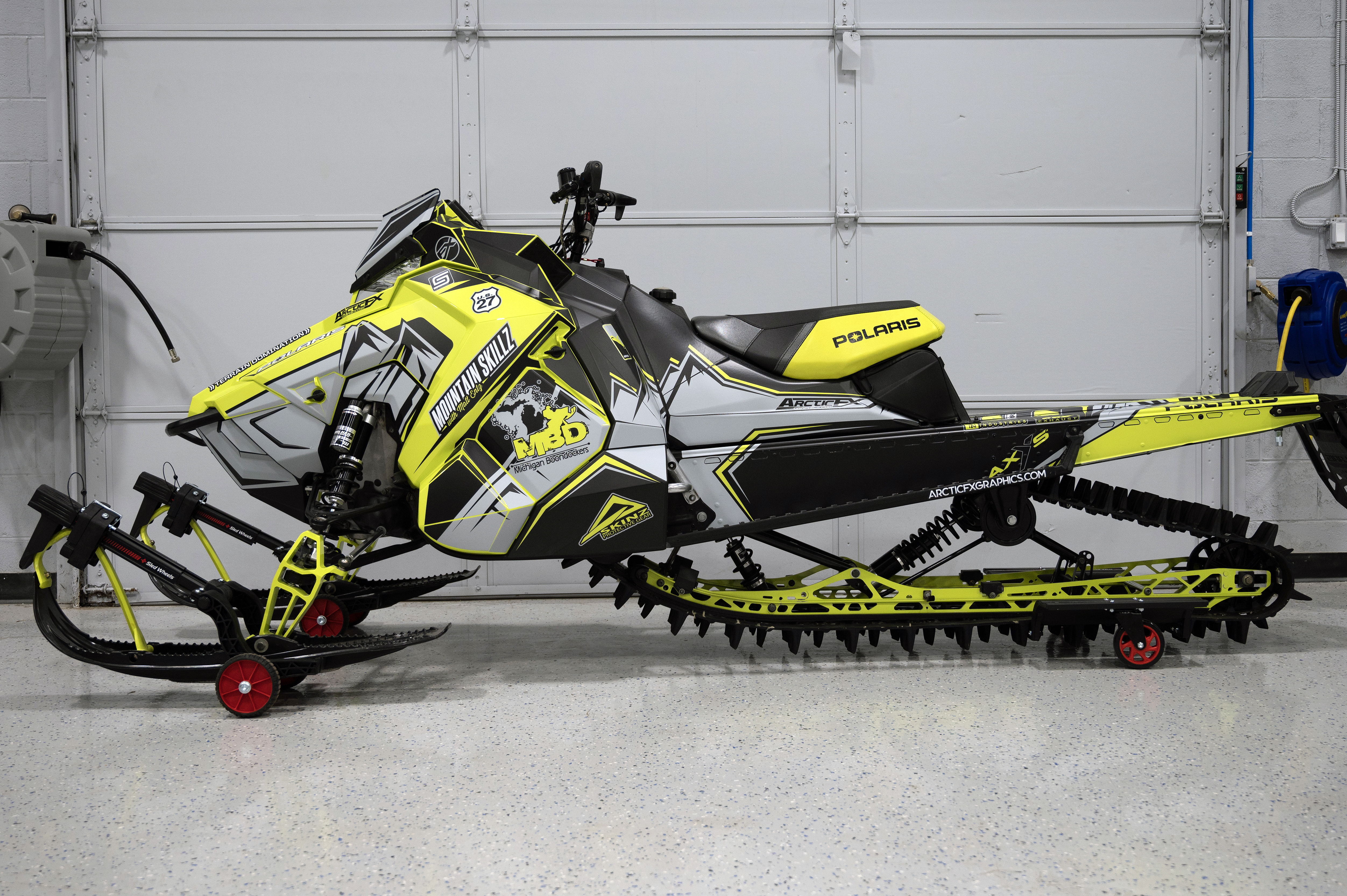 A Polaris Axys Mountain snowmobile with a lime squeeze, gray, and black Teton custom vinyl wrap.