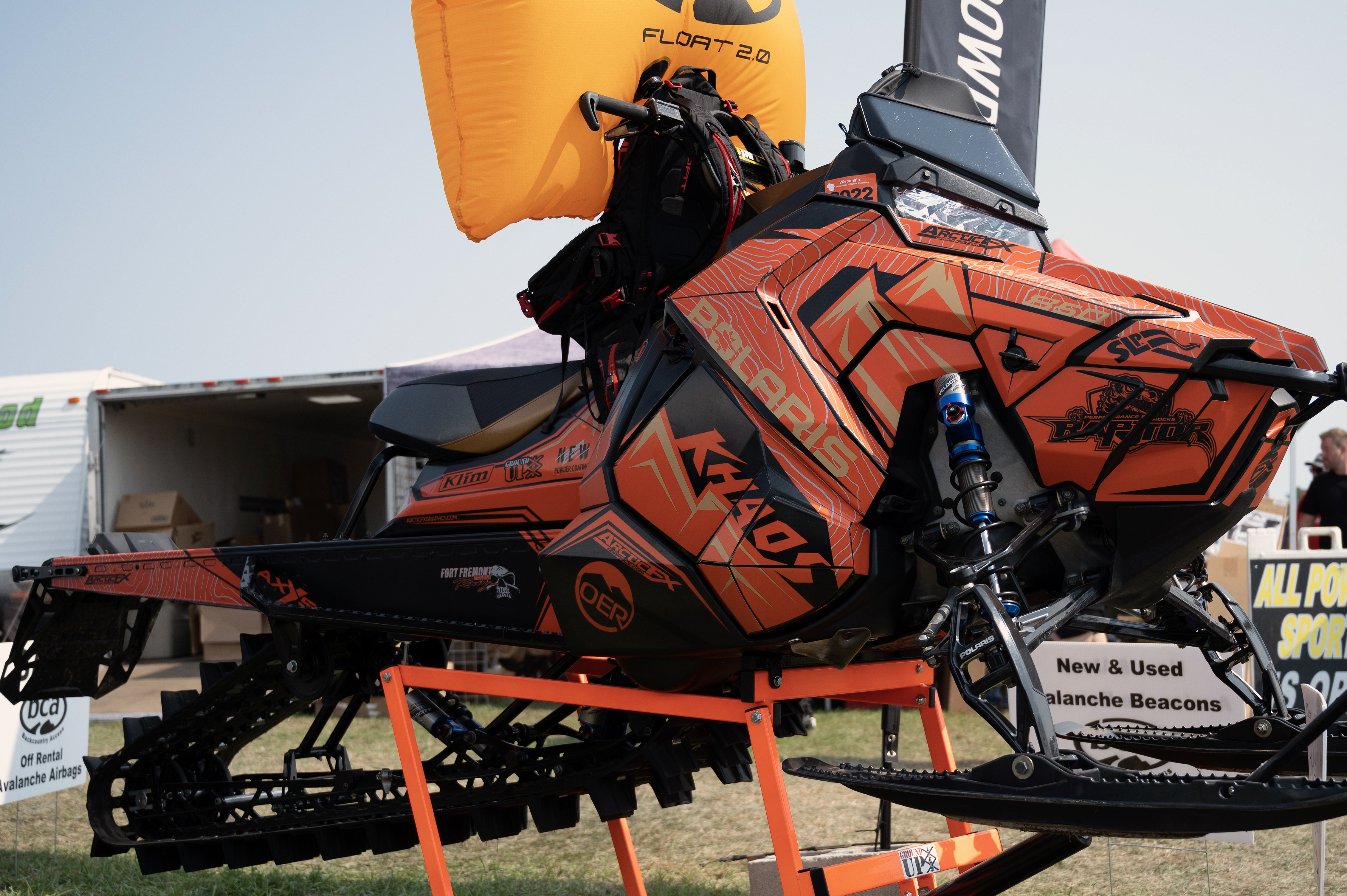 A Polaris Axys Mountain snowmobile with a orange, tan, and black Teton custom vinyl wrap.