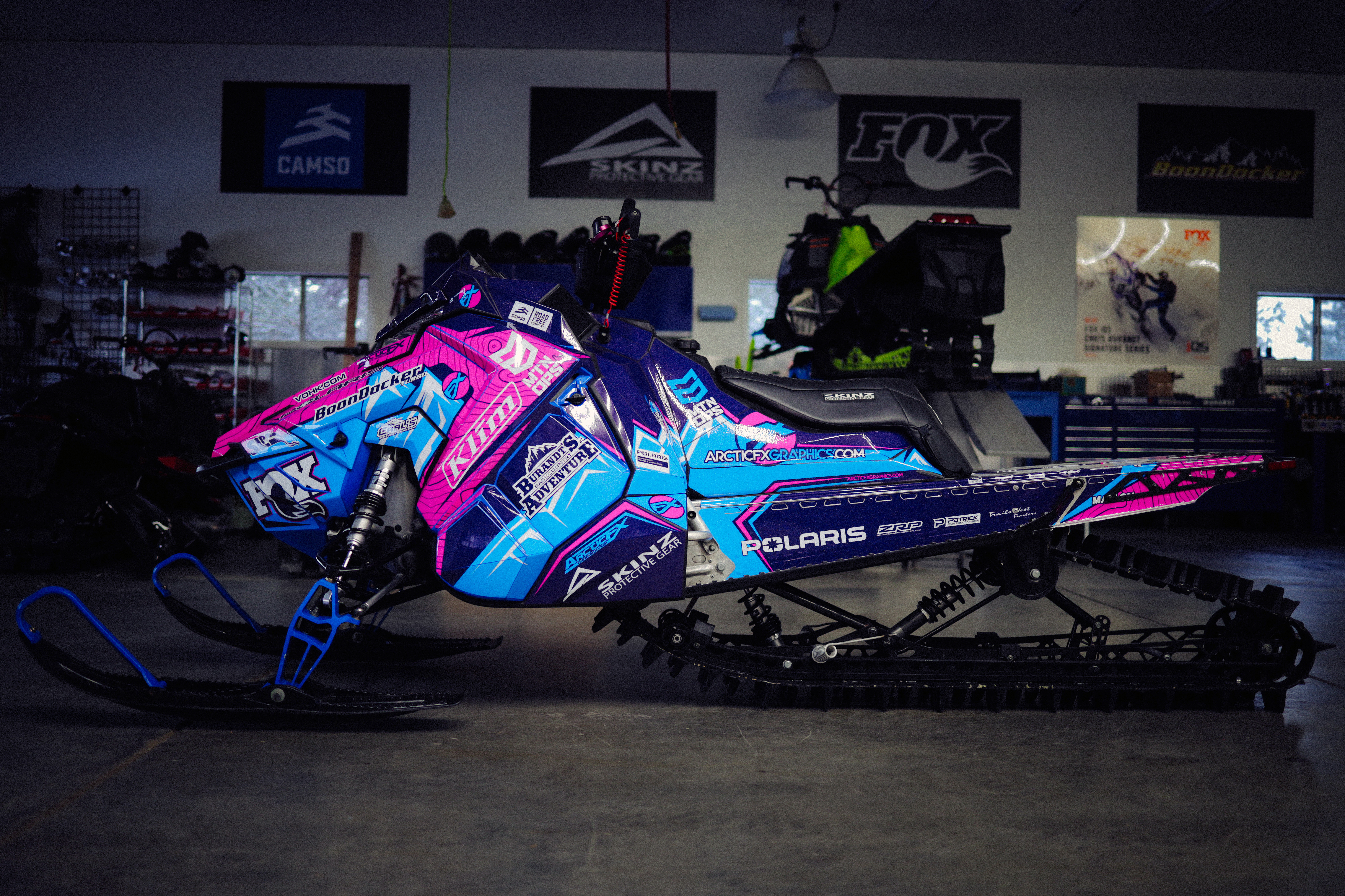 A Polaris Axys Mountain snowmobile with a pink, blue, and white Teton custom vinyl wrap.