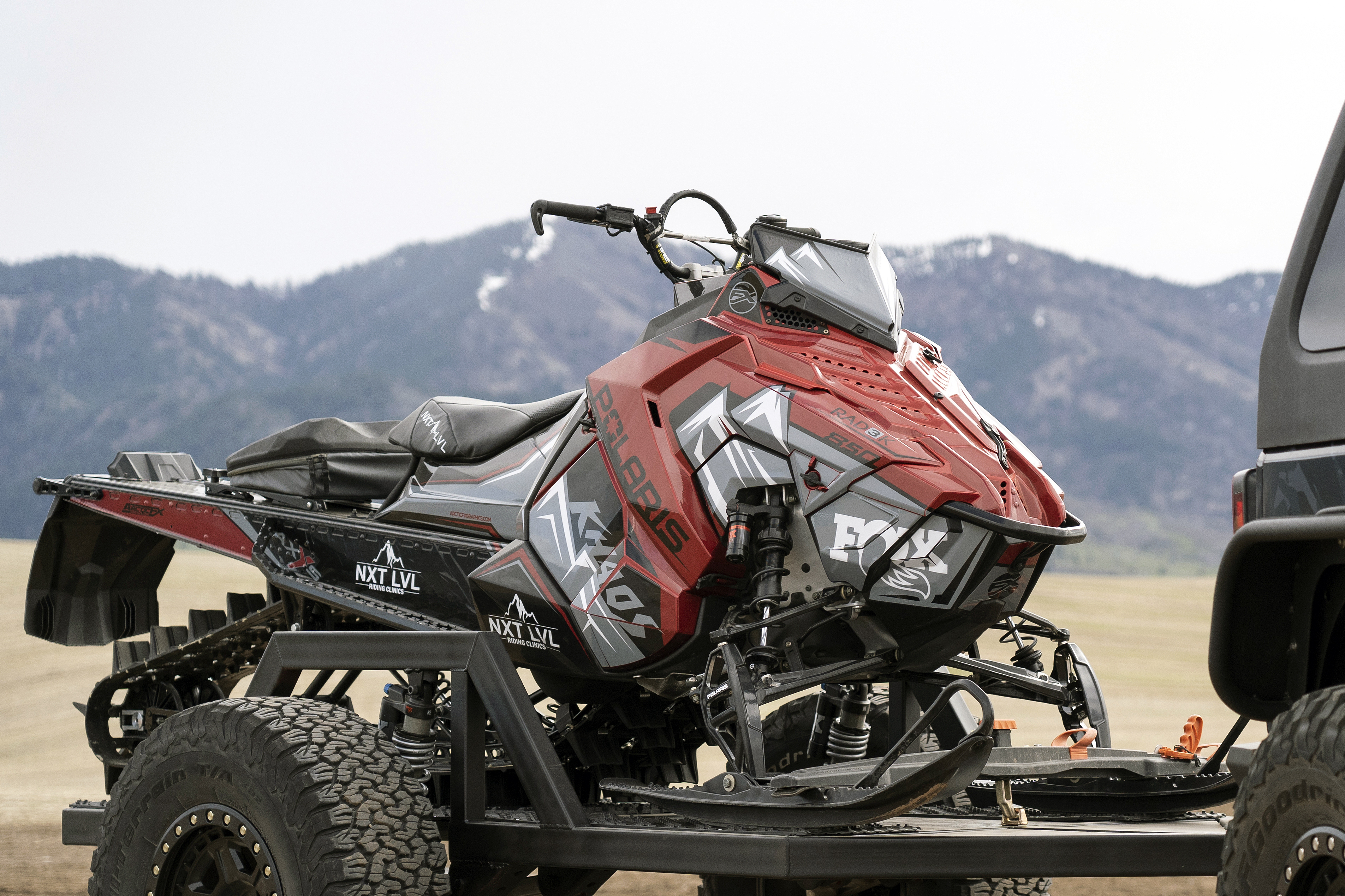A Polaris Axys Mountain snowmobile with a red, gray, and black Teton custom vinyl wrap.