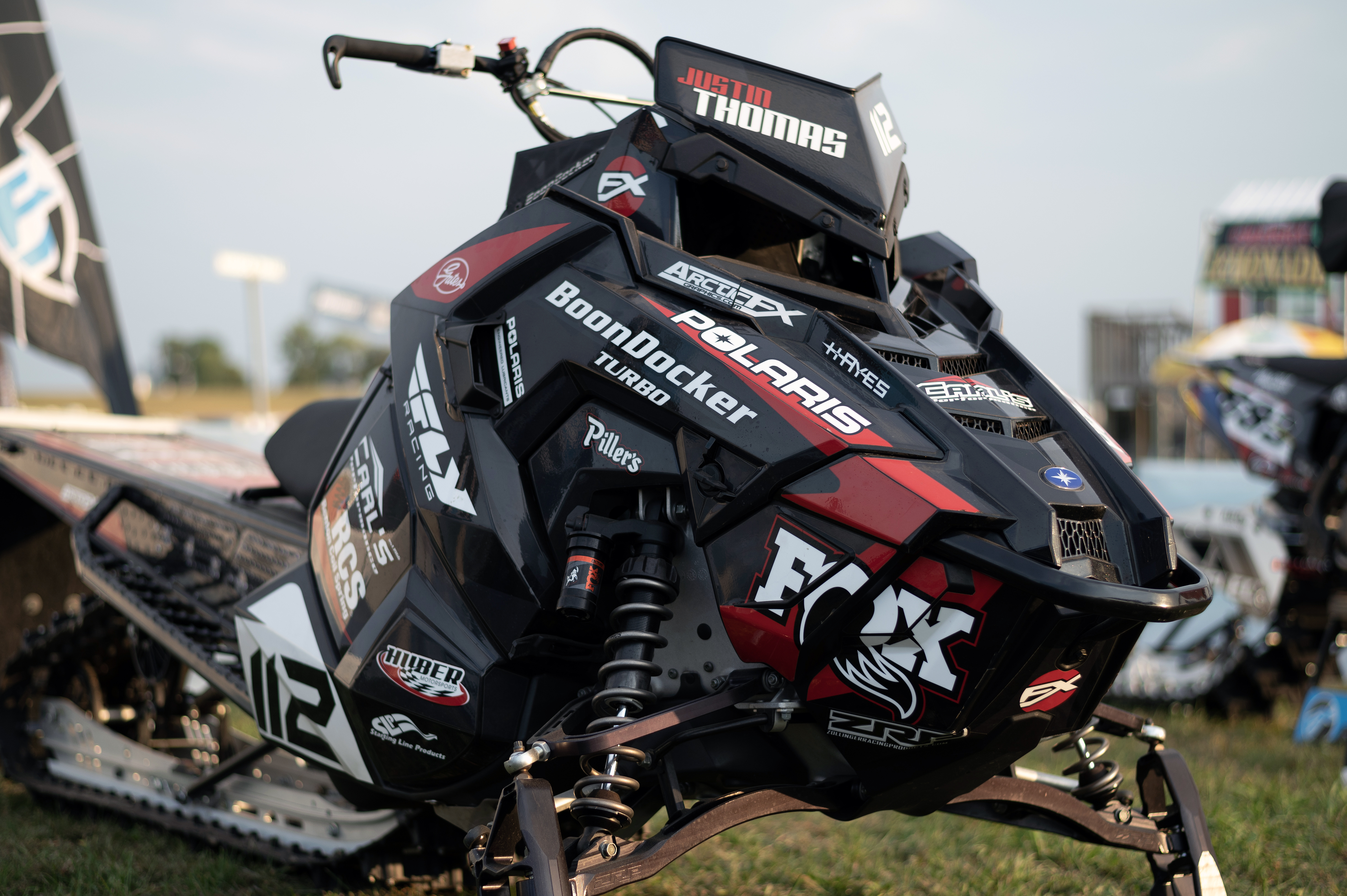A Polaris Axys Mountain snowmobile with a red, white, and black Justin Thomas Velocity custom vinyl wrap.