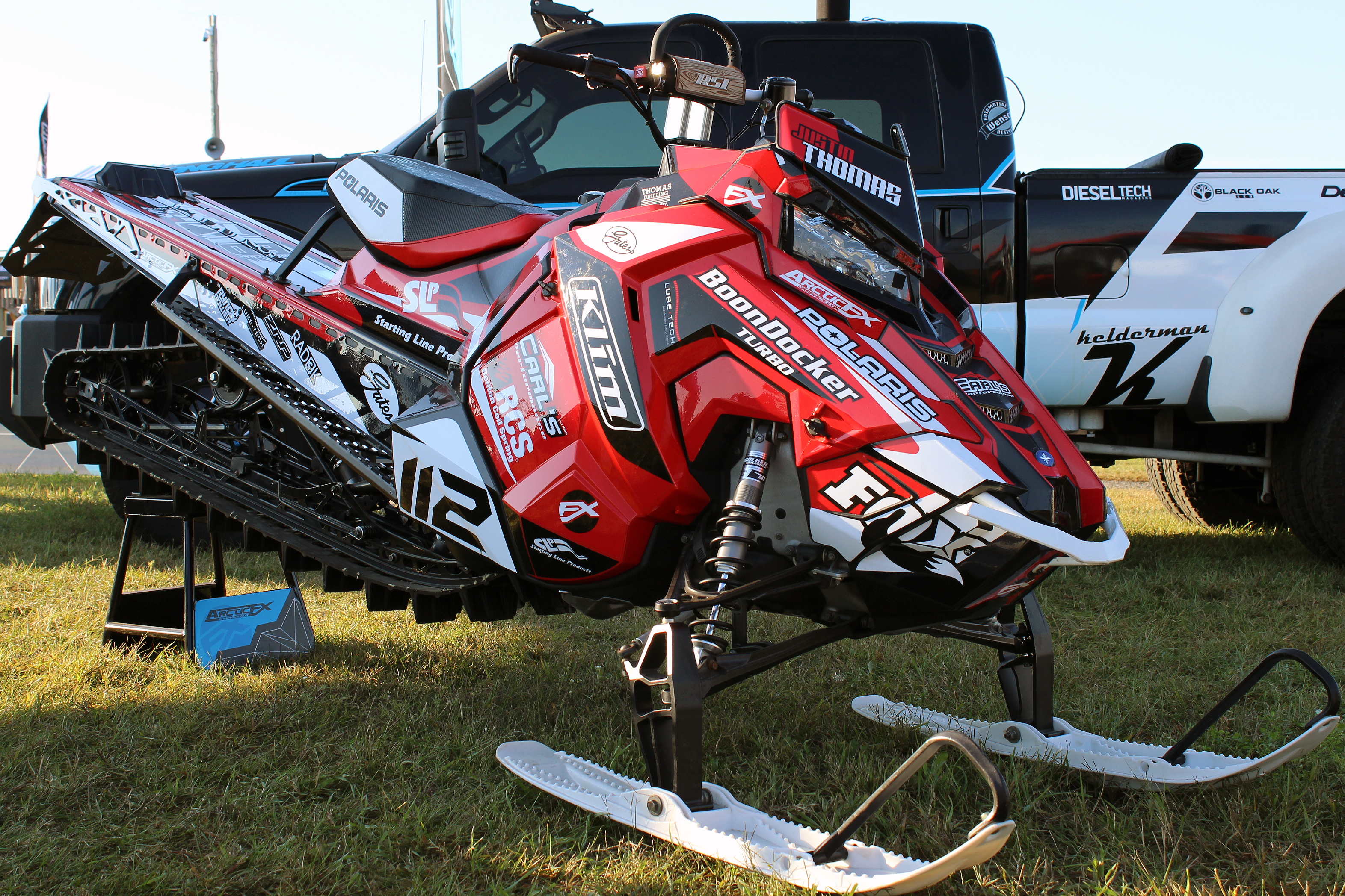A Polaris Axys Mountain snowmobile with a red, black, white, and black Justin Thomas Velocity custom vinyl wrap.