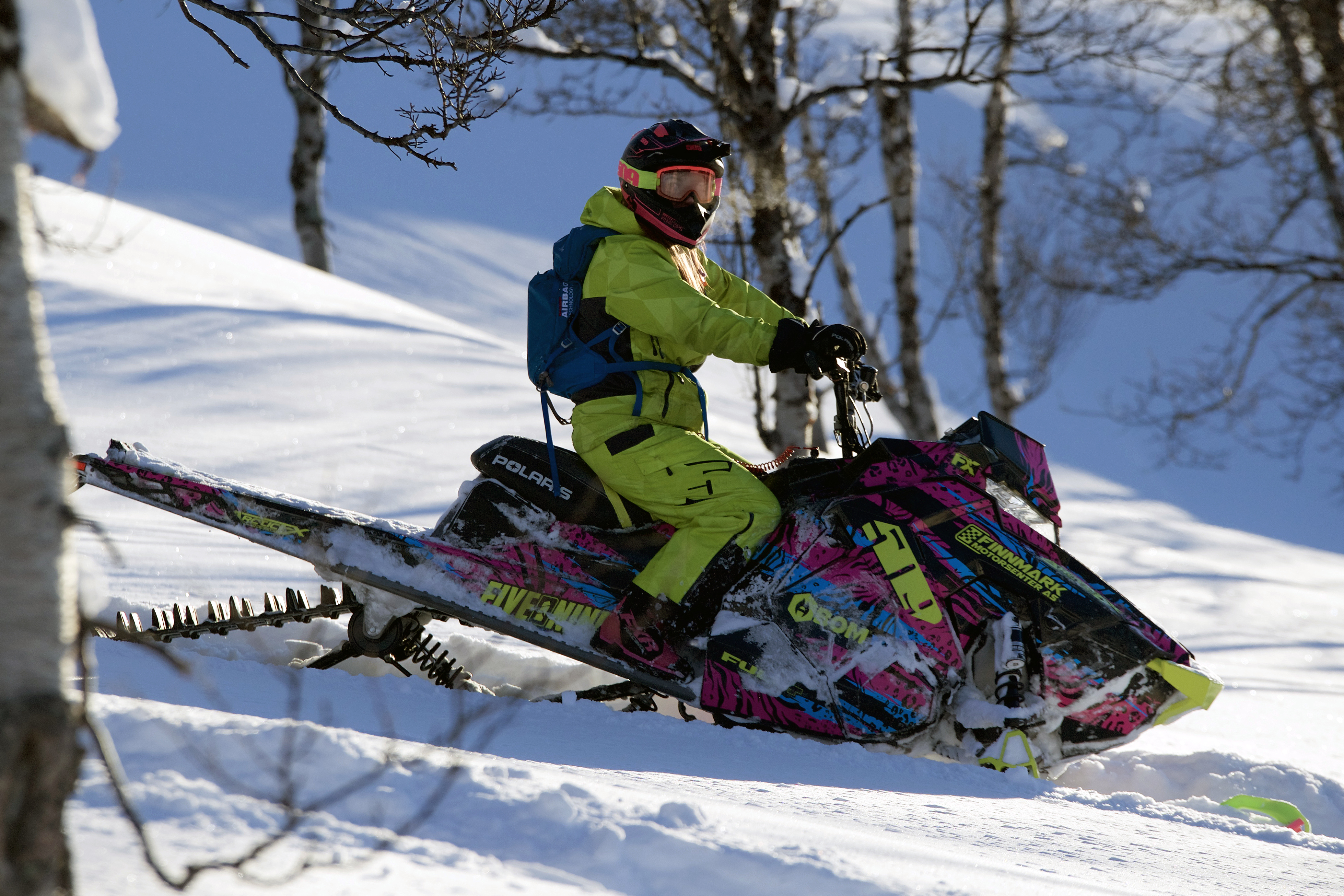 A Polaris Axys Mountain snowmobile with a pink, blue, and lime squeeze Threshold custom vinyl wrap.