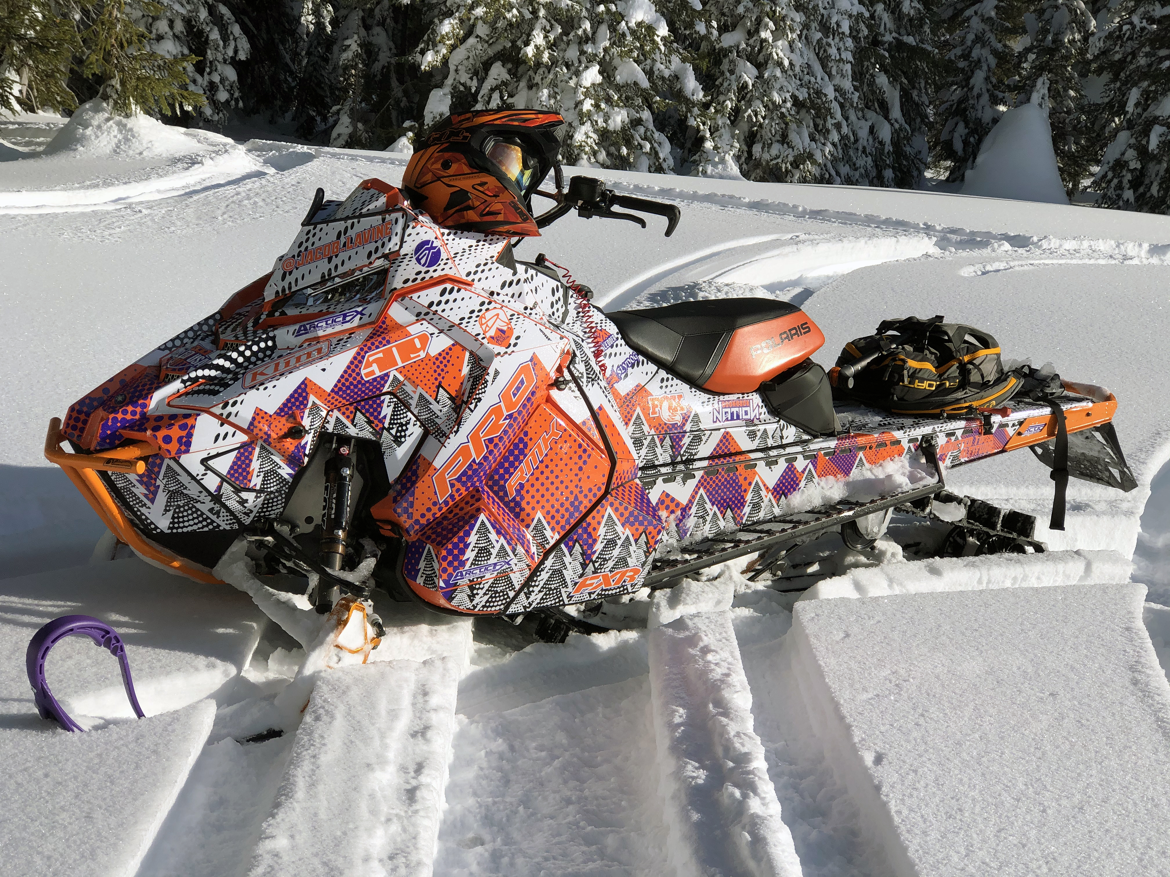 A Polaris Axys Mountain snowmobile with a white, purple, and orange Vertex custom vinyl wrap.