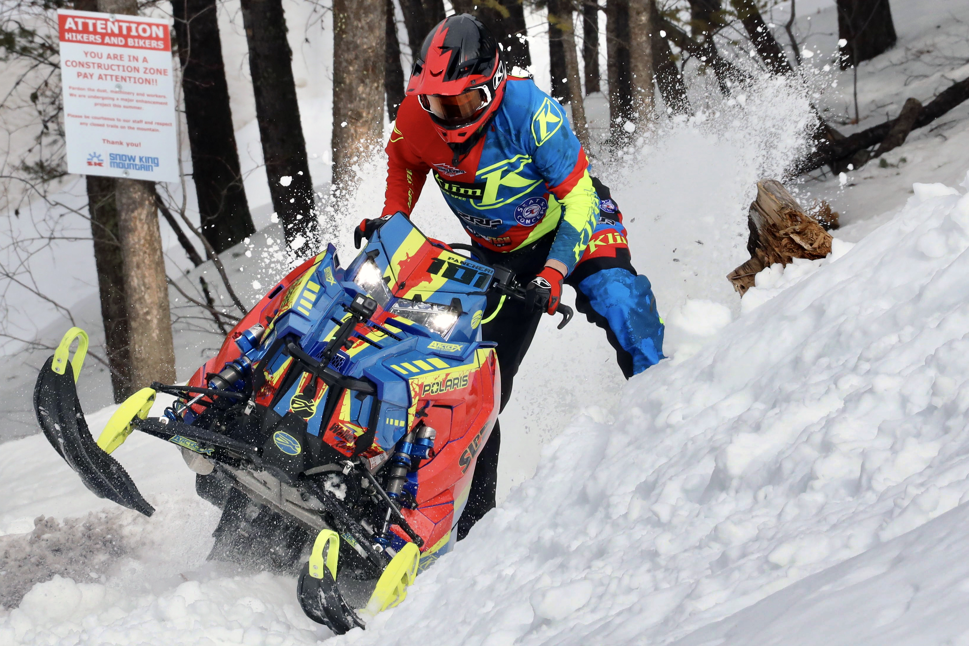 A Polaris Axys Mountain snowmobile with a blue, lime squeeze, and orange Vision custom vinyl wrap.
