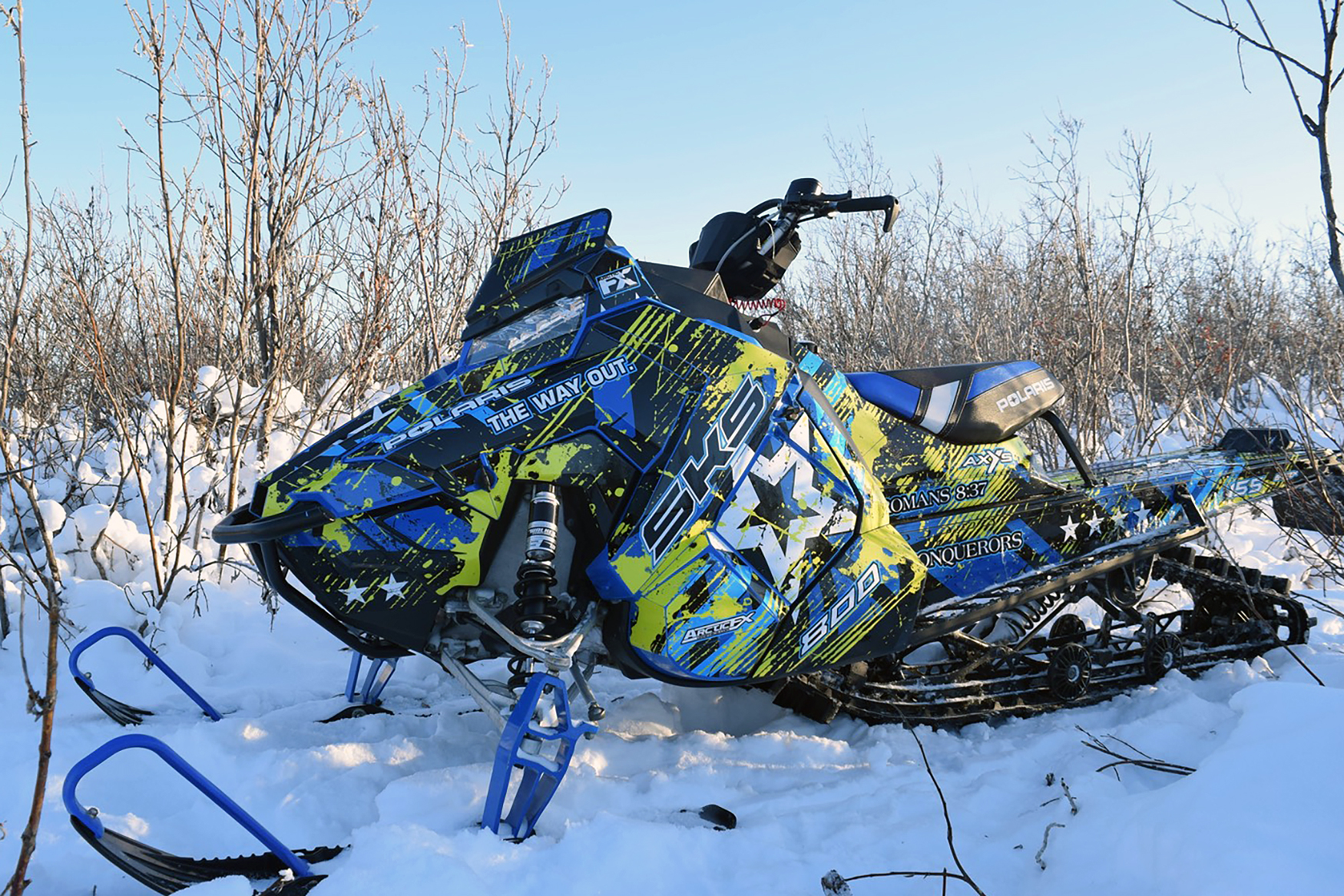 A Polaris Axys Mountain snowmobile with a lime squeeze, black, and blue Wartorn custom vinyl wrap.