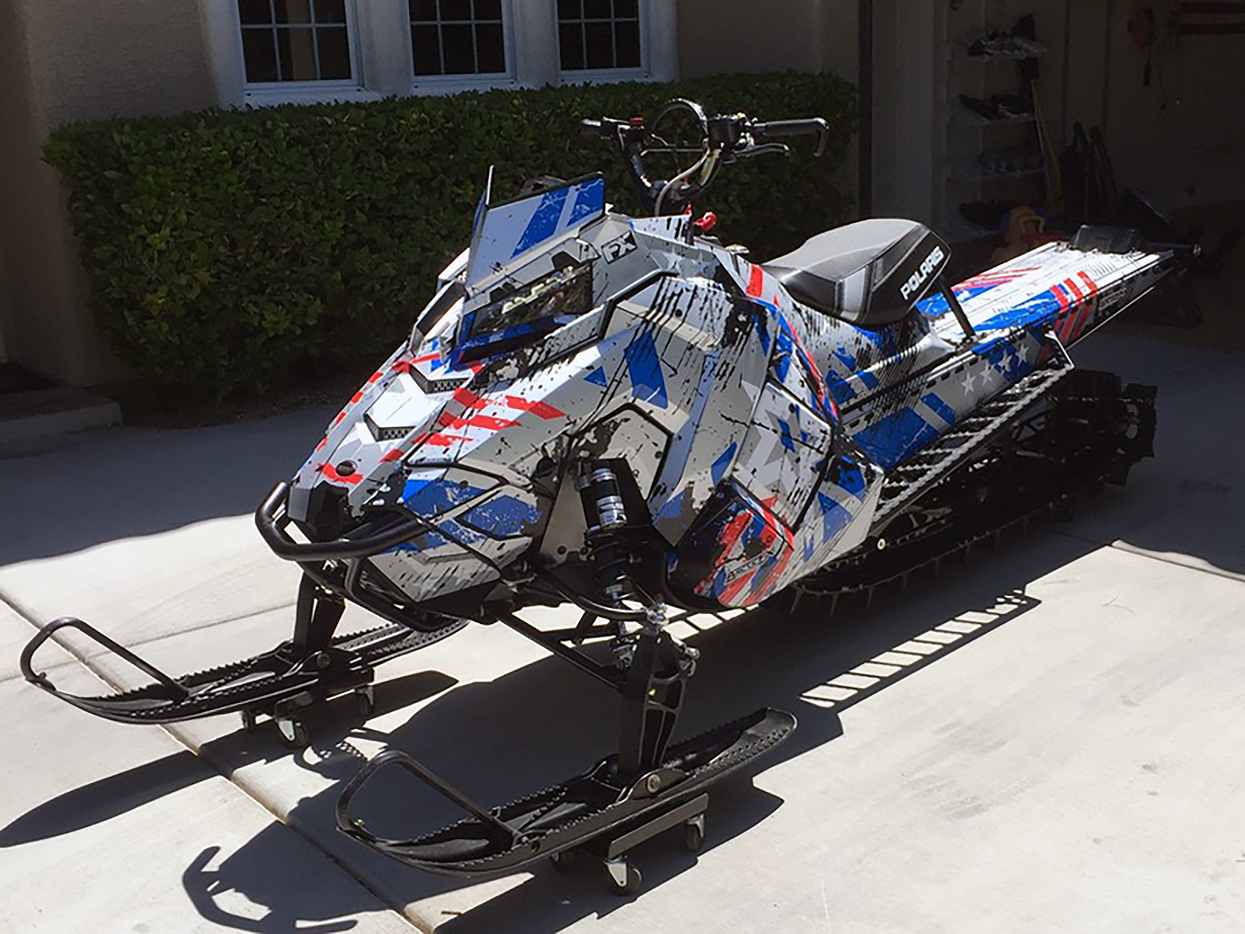 A Polaris Axys Mountain snowmobile with a red, black, and blue Wartorn custom vinyl wrap.