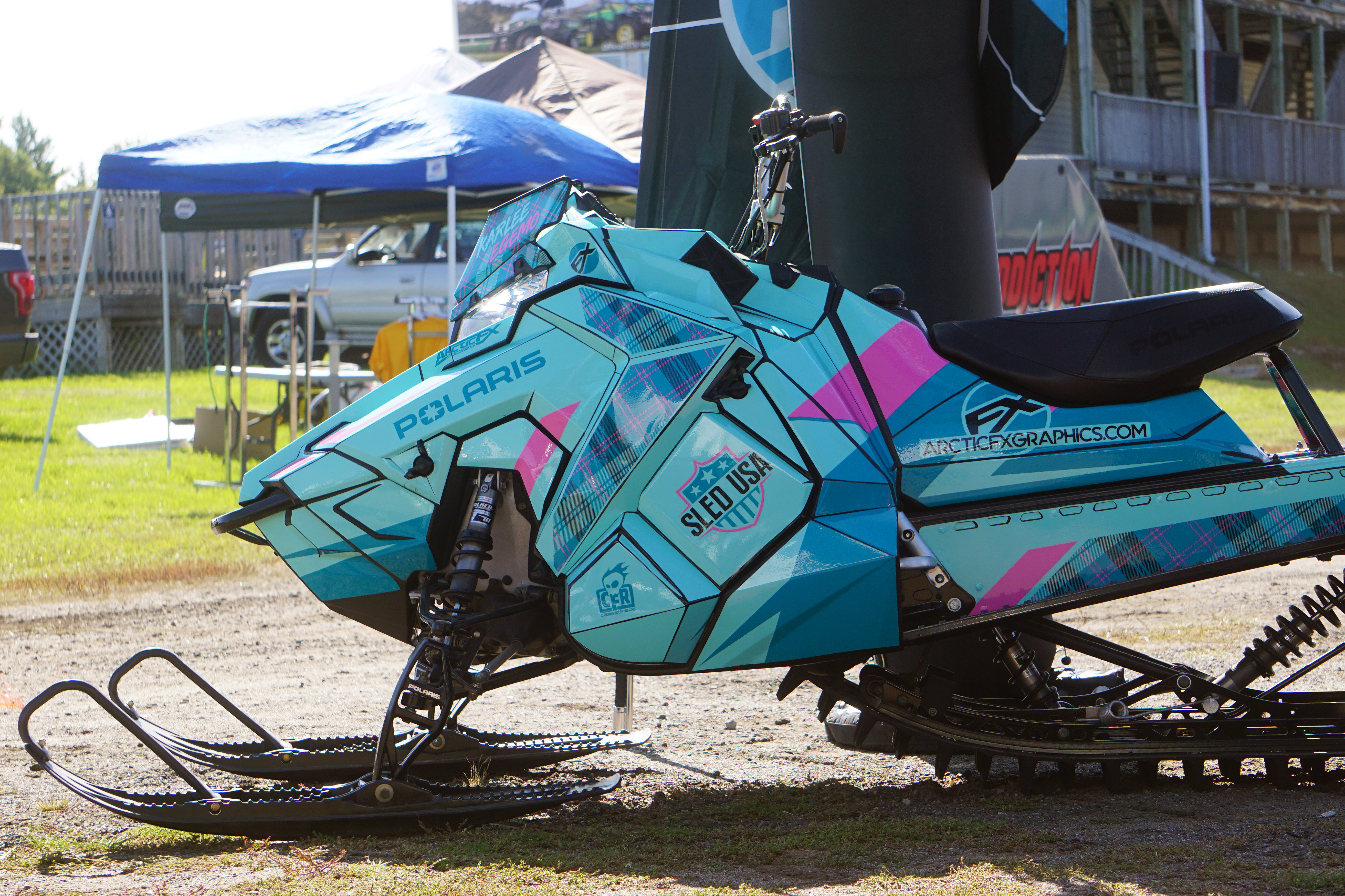 A Polaris Axys Mountain snowmobile with a pink, black, and blue Wartorn custom vinyl wrap.