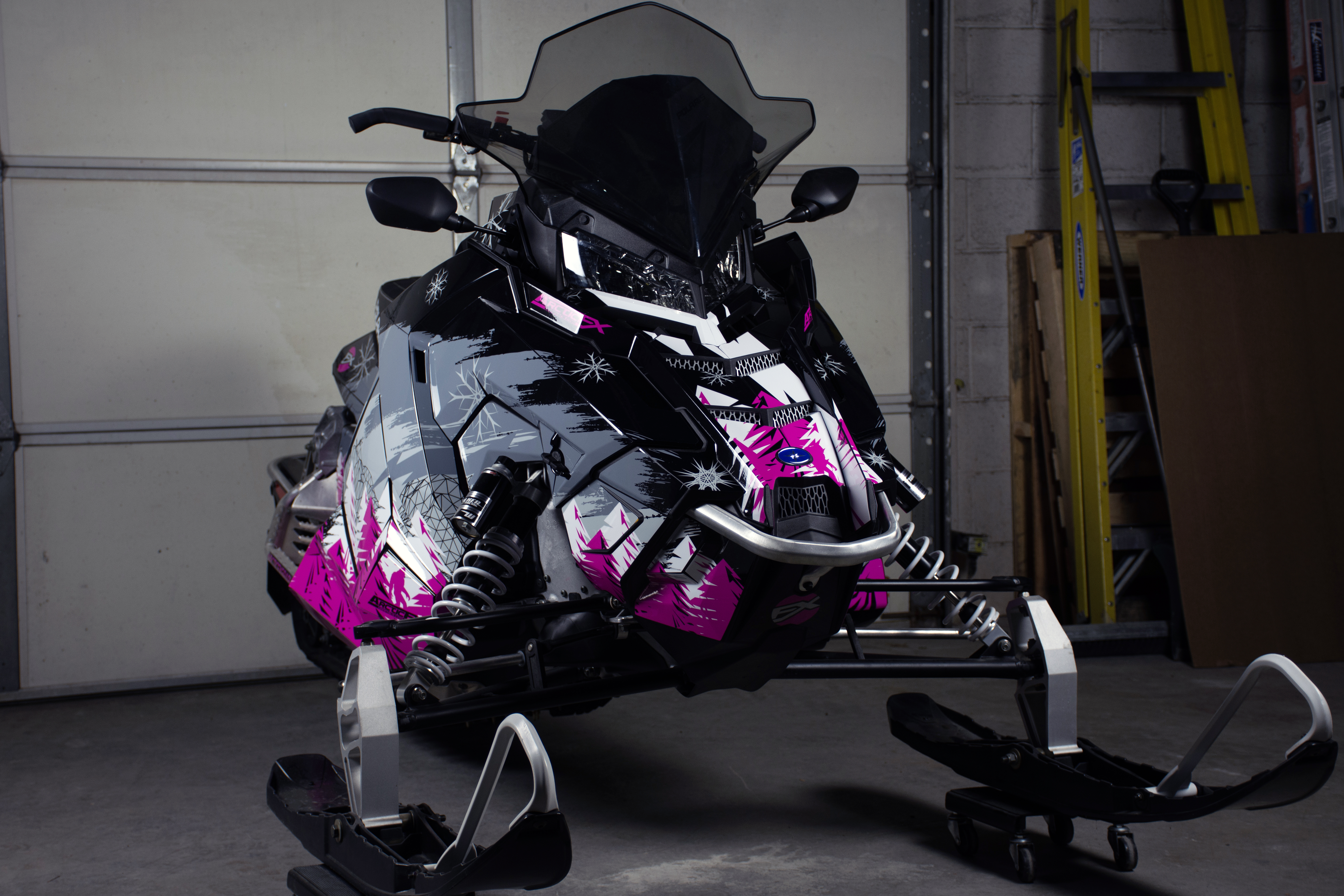 A Polaris Axys Trail snowmobile with a pink, black, and white Absolute Zero custom vinyl wrap.