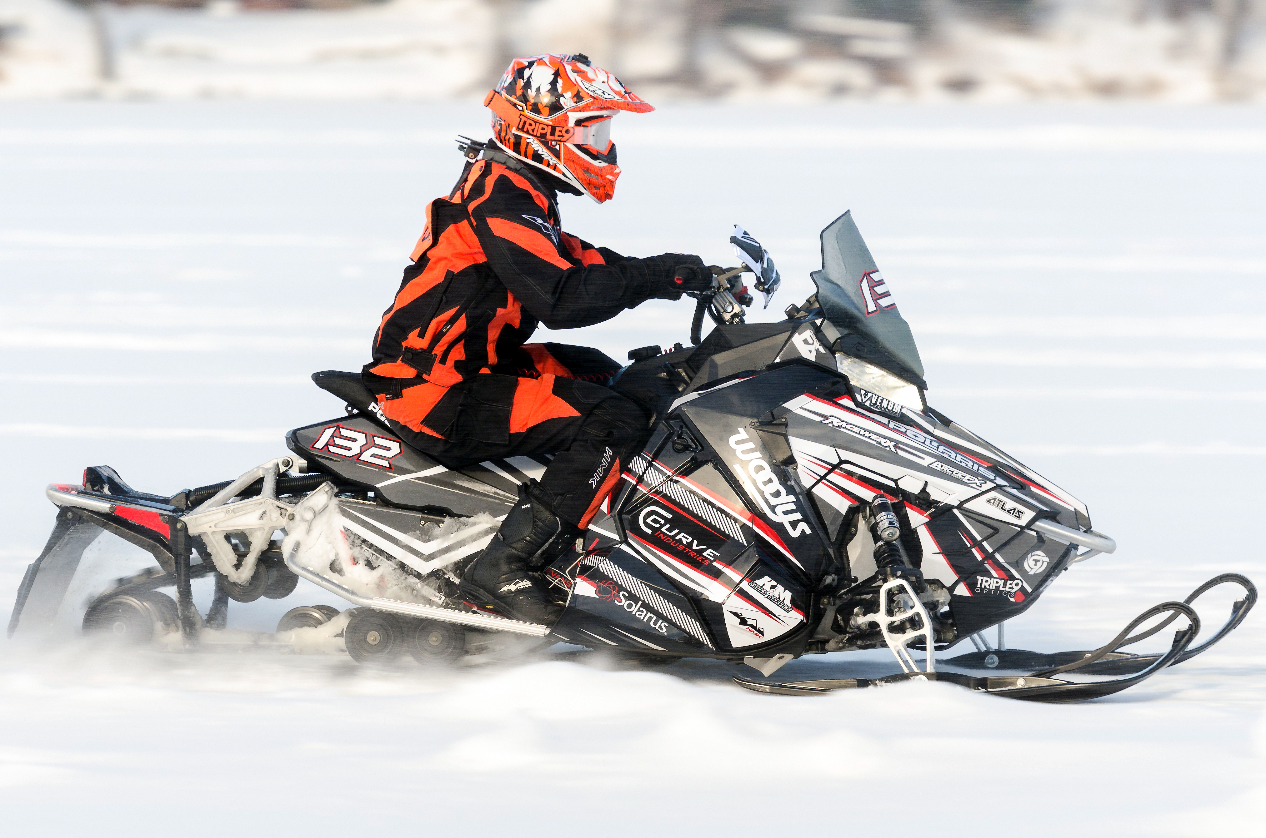 A Polaris Axys Trail snowmobile with a red, gray, and white Bred2Win custom vinyl wrap.