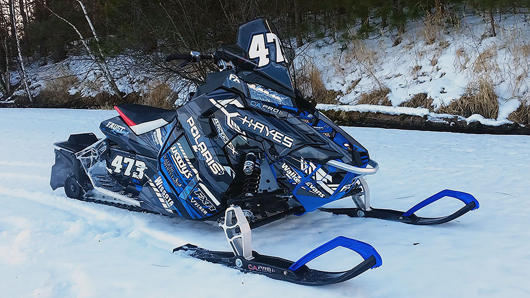 A Polaris Axys Trail snowmobile with a black, white, and blue stripes Evasion custom vinyl wrap.