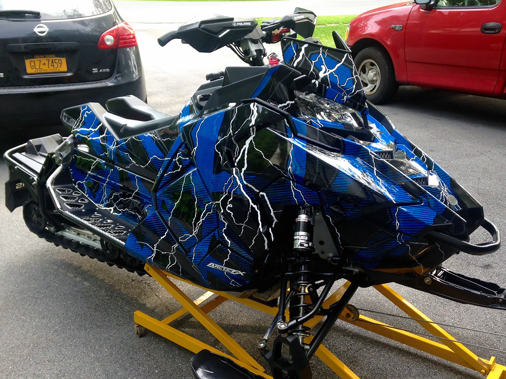 A Polaris Axys Trail snowmobile with a black, white, and blue lightning Hard Rain custom vinyl wrap.