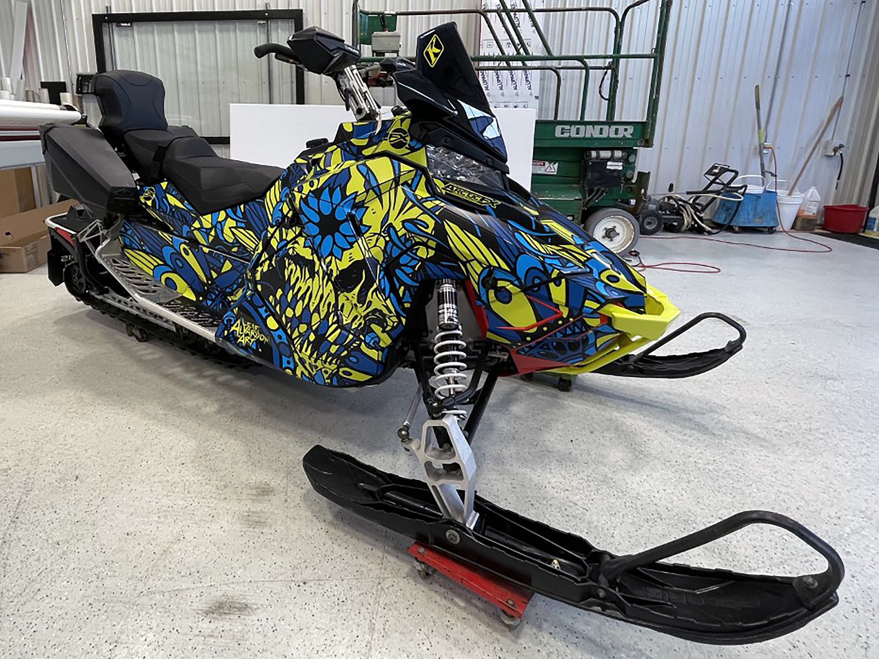 A Polaris Axys Trail snowmobile with a lime squeeze, black, and blue Leif Alvarsson Calavera custom vinyl wrap.