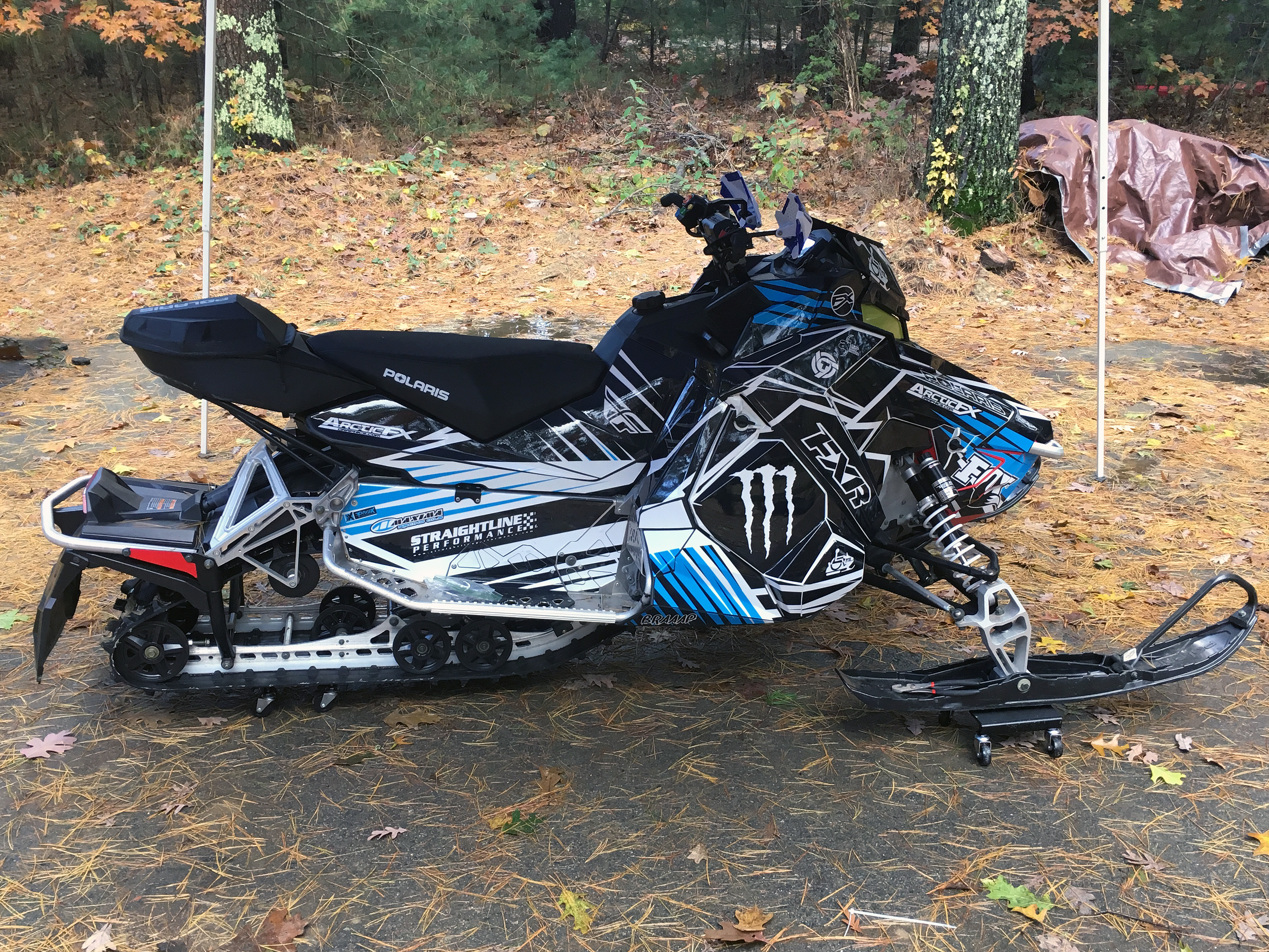 A Polaris Axys Trail snowmobile with a black, white, and blue Kryptonite custom vinyl wrap.