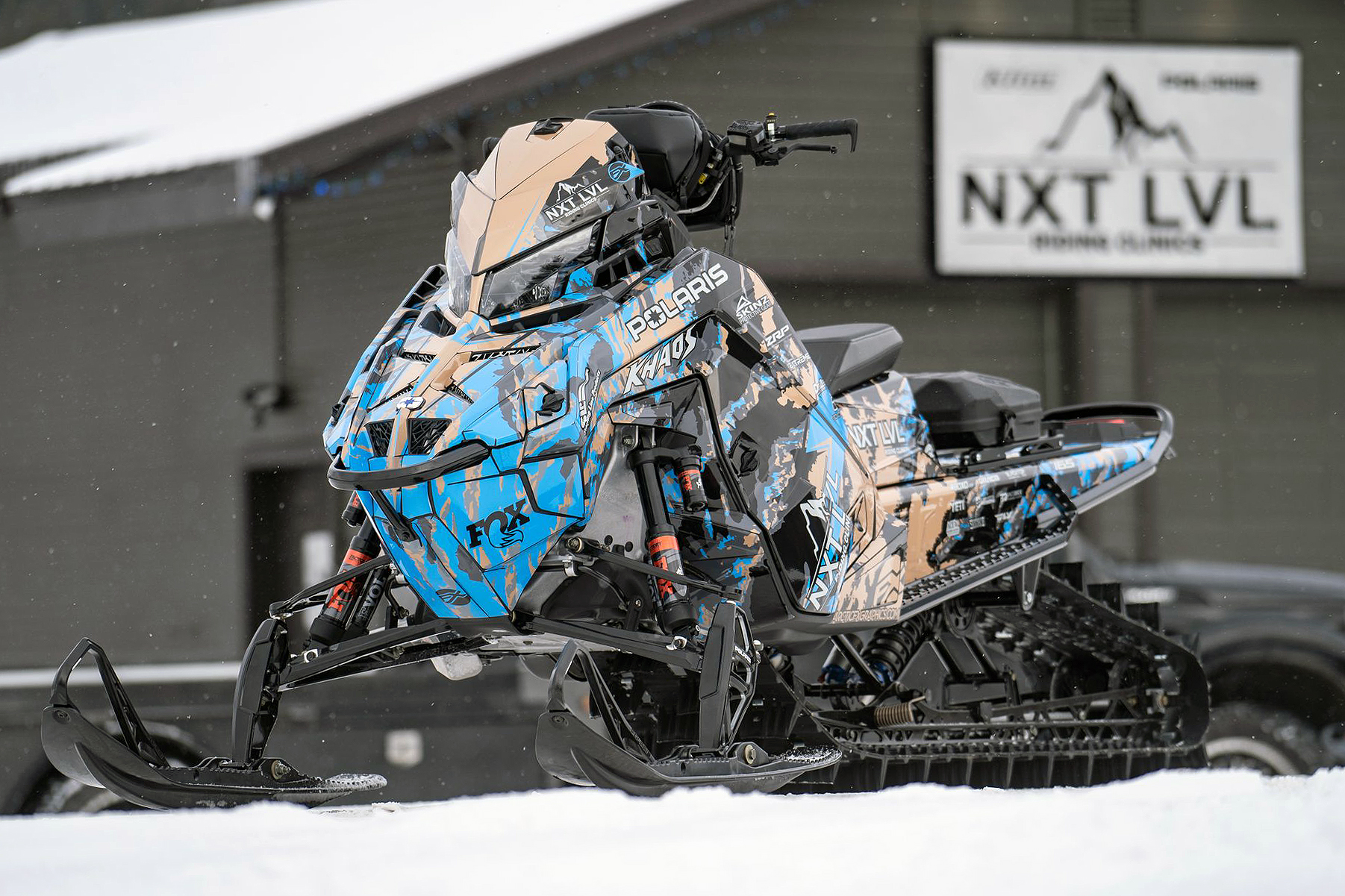 A Polaris Matryx Mountain snowmobile with a blue, tan, and black Adams Inversion custom vinyl wrap.