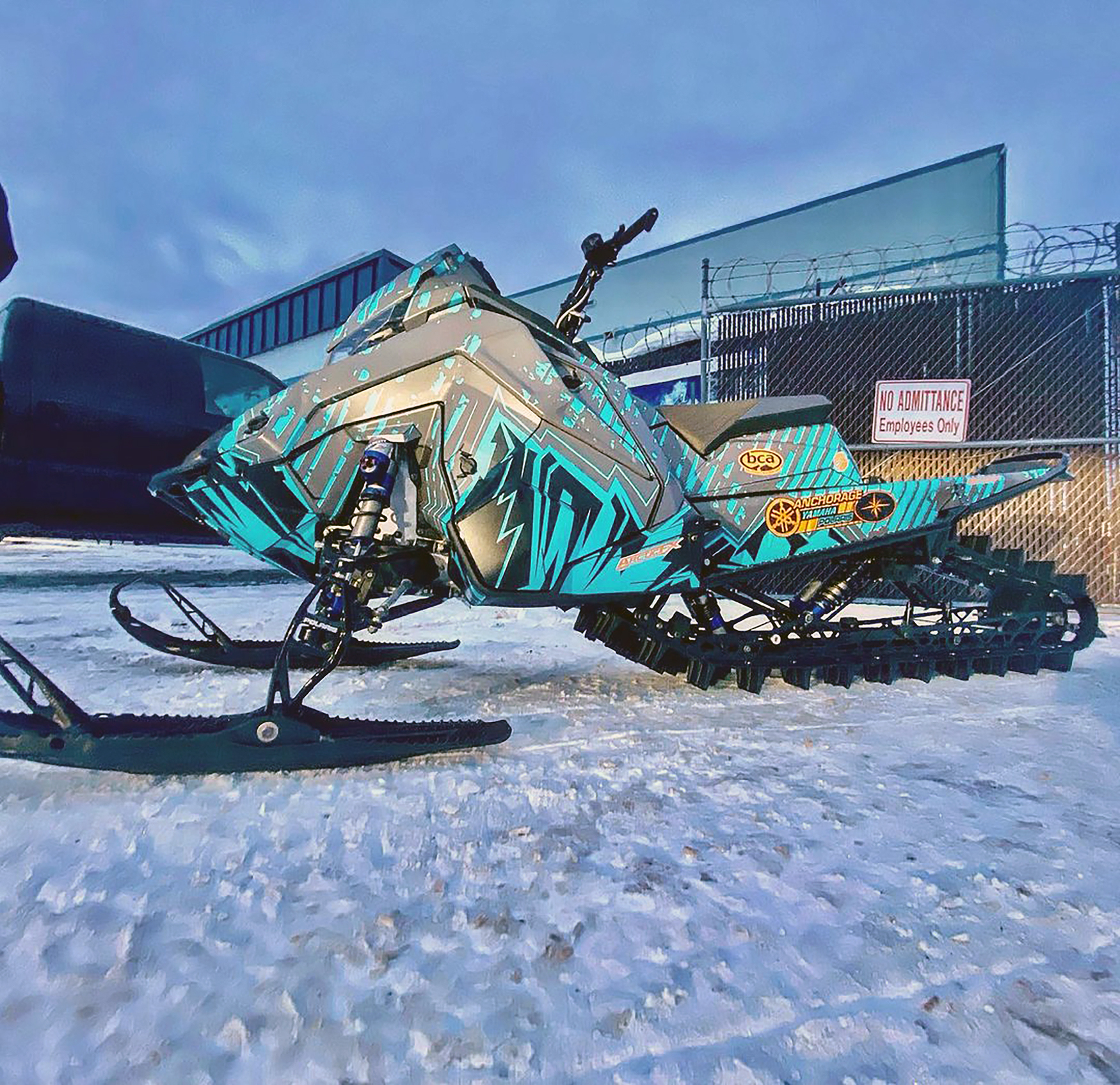 A Polaris Matryx Mountain snowmobile with a blue, orange, black, and gray Altitude custom vinyl wrap.