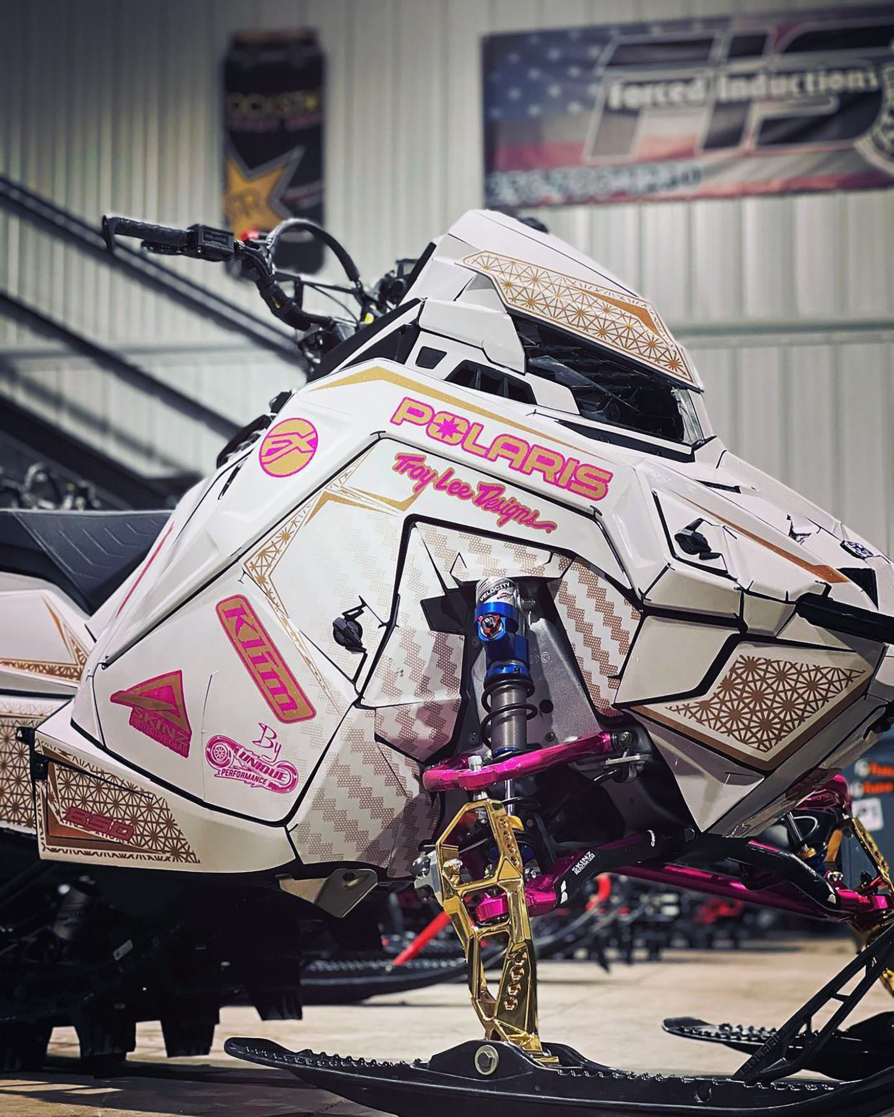 A Polaris Matryx Mountain snowmobile with a pink, white, and tan Atomic custom vinyl wrap.