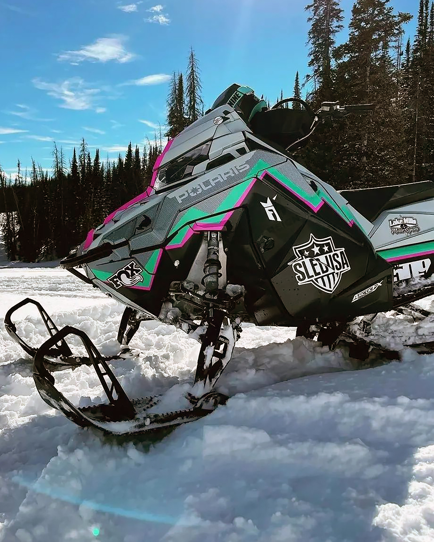 A Polaris Matryx Mountain snowmobile with a white, black, pink, and aqua Burandt Incognito custom vinyl wrap.
