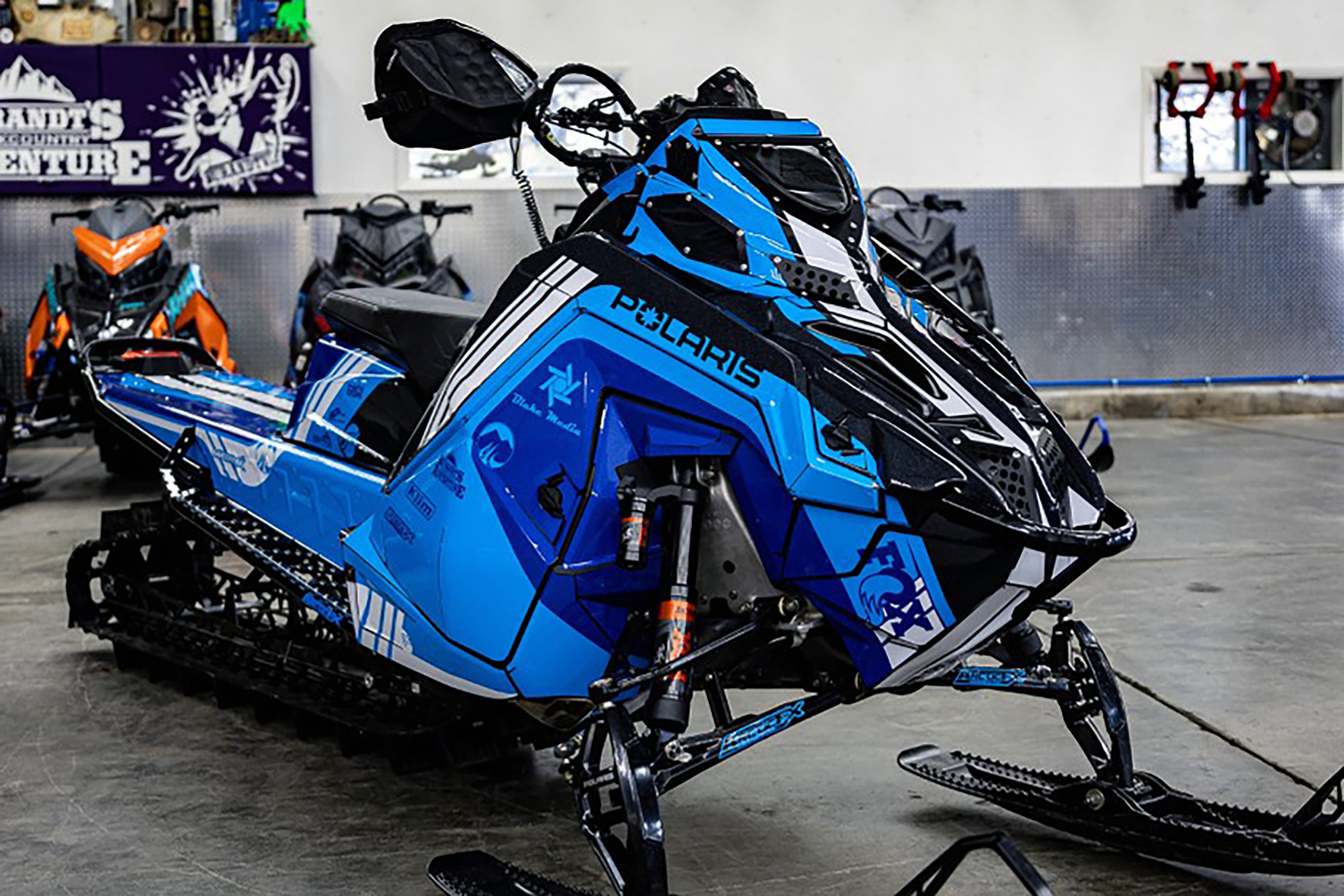 A Polaris Matryx Mountain snowmobile with a white, blue, and black Cobra MC custom vinyl wrap.