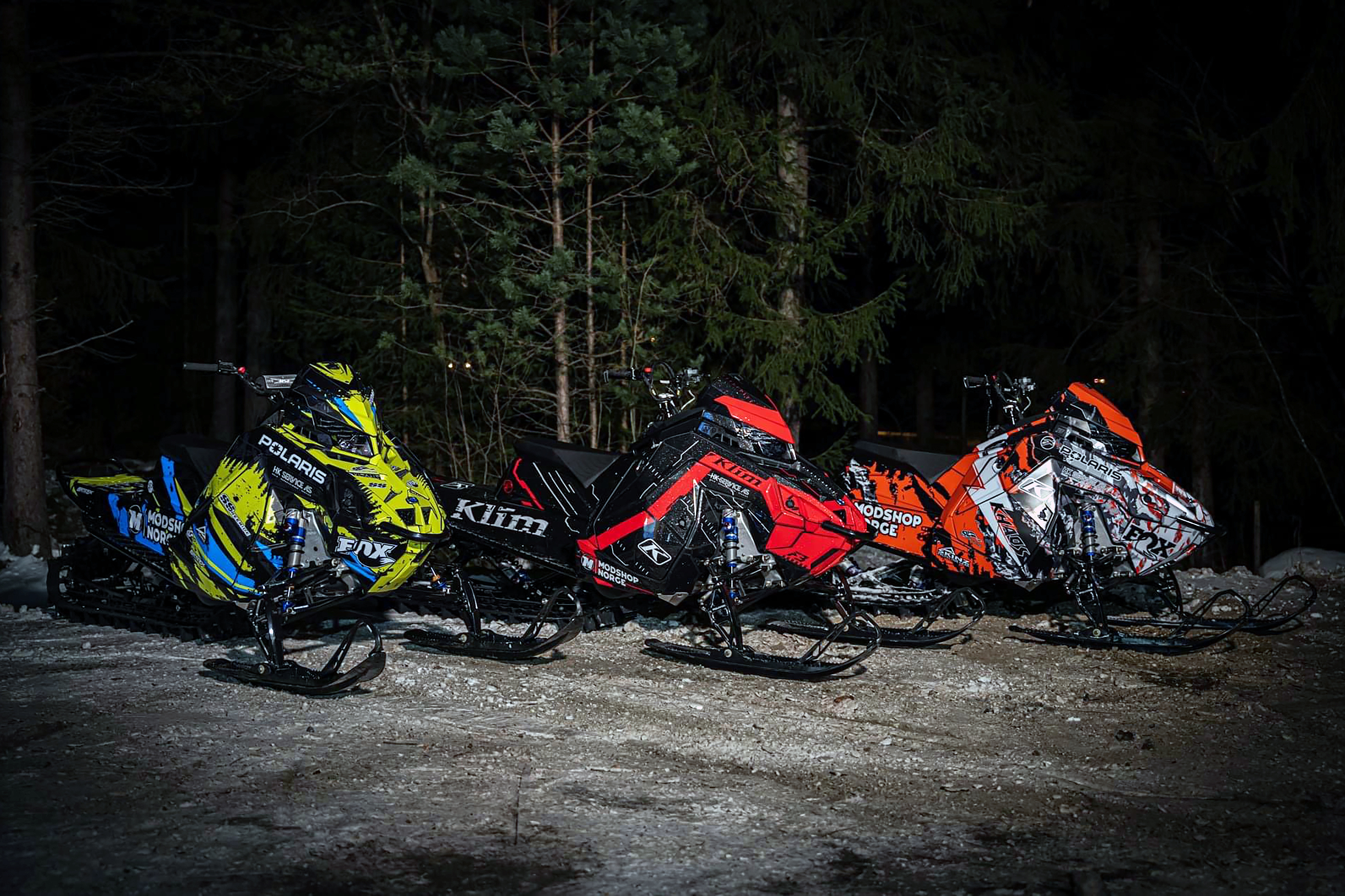 Three Polaris Matryx Mountain snowmobiles with colorful unique custom vinyl wraps.