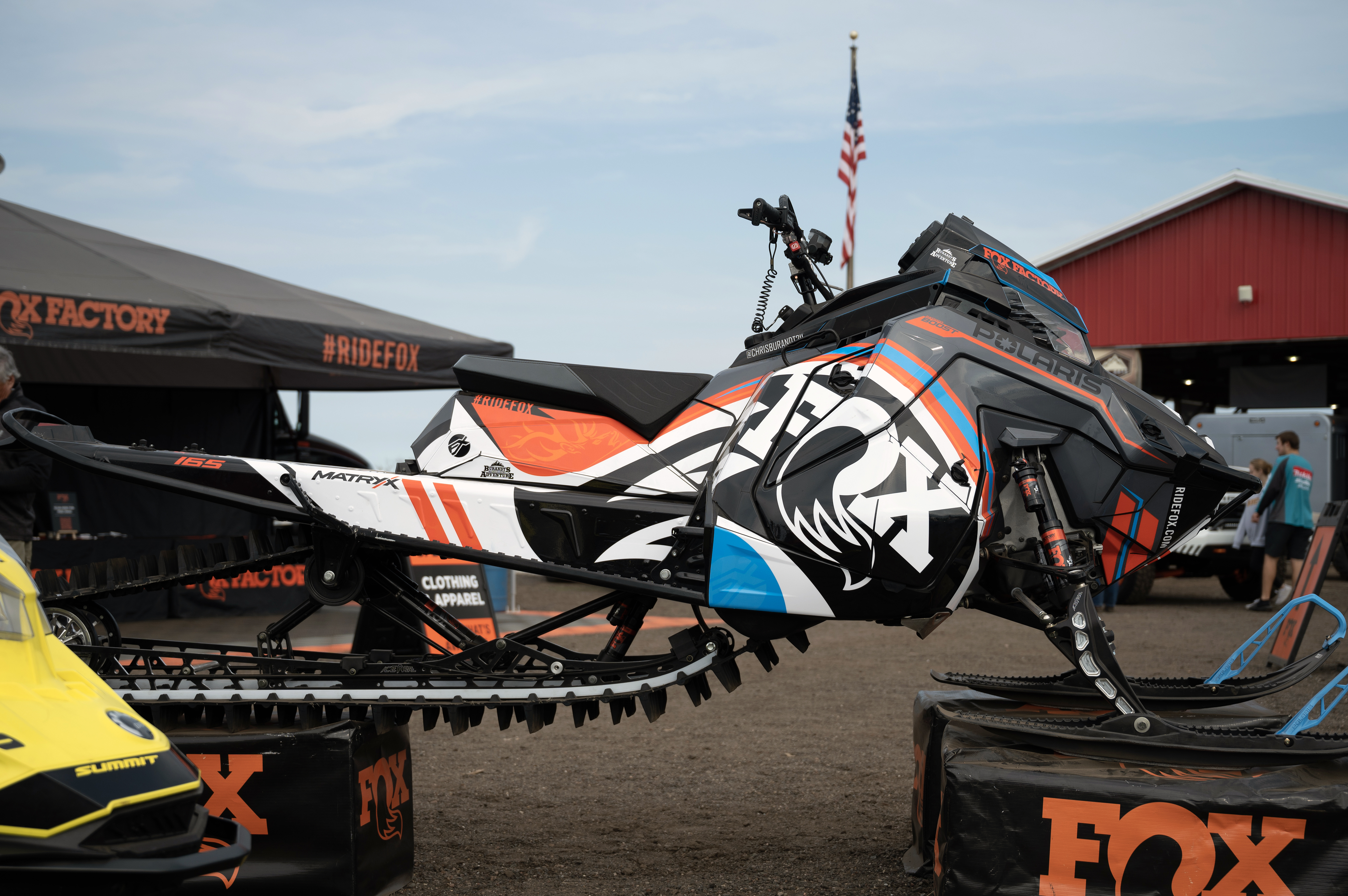 A Polaris Matryx Mountain snowmobile with a blue, gray, and black Fox Rebound custom vinyl wrap.