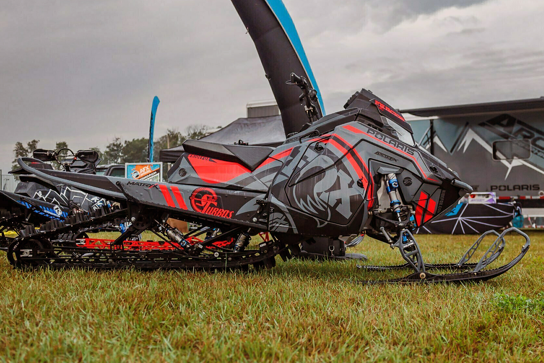 A Polaris Matryx Mountain snowmobile with a red, gray, and black Fox Rebound custom vinyl wrap.