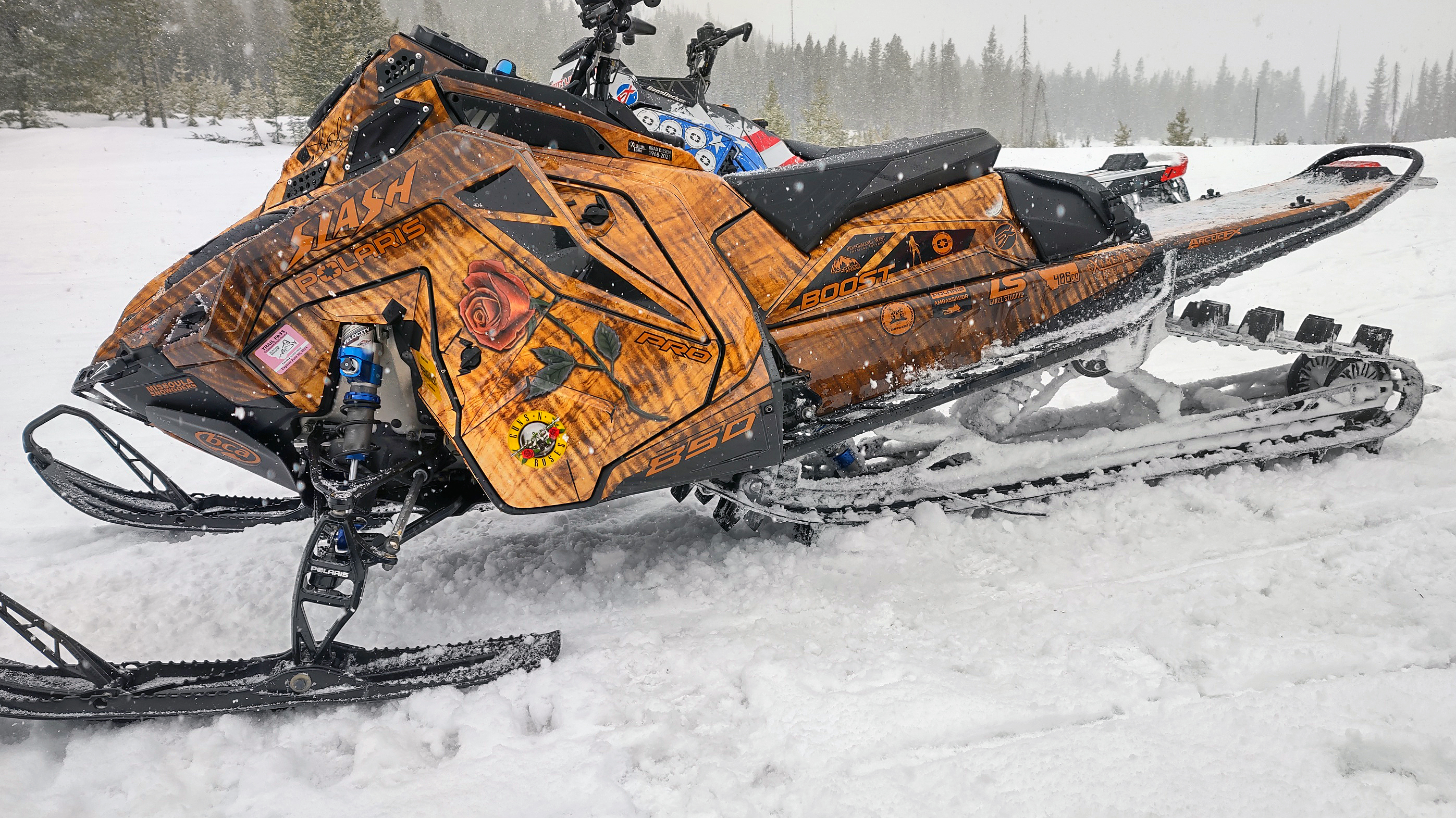 A Polaris Matryx Mountain snowmobile with a wood stain guitar Guns and Roses custom vinyl wrap.