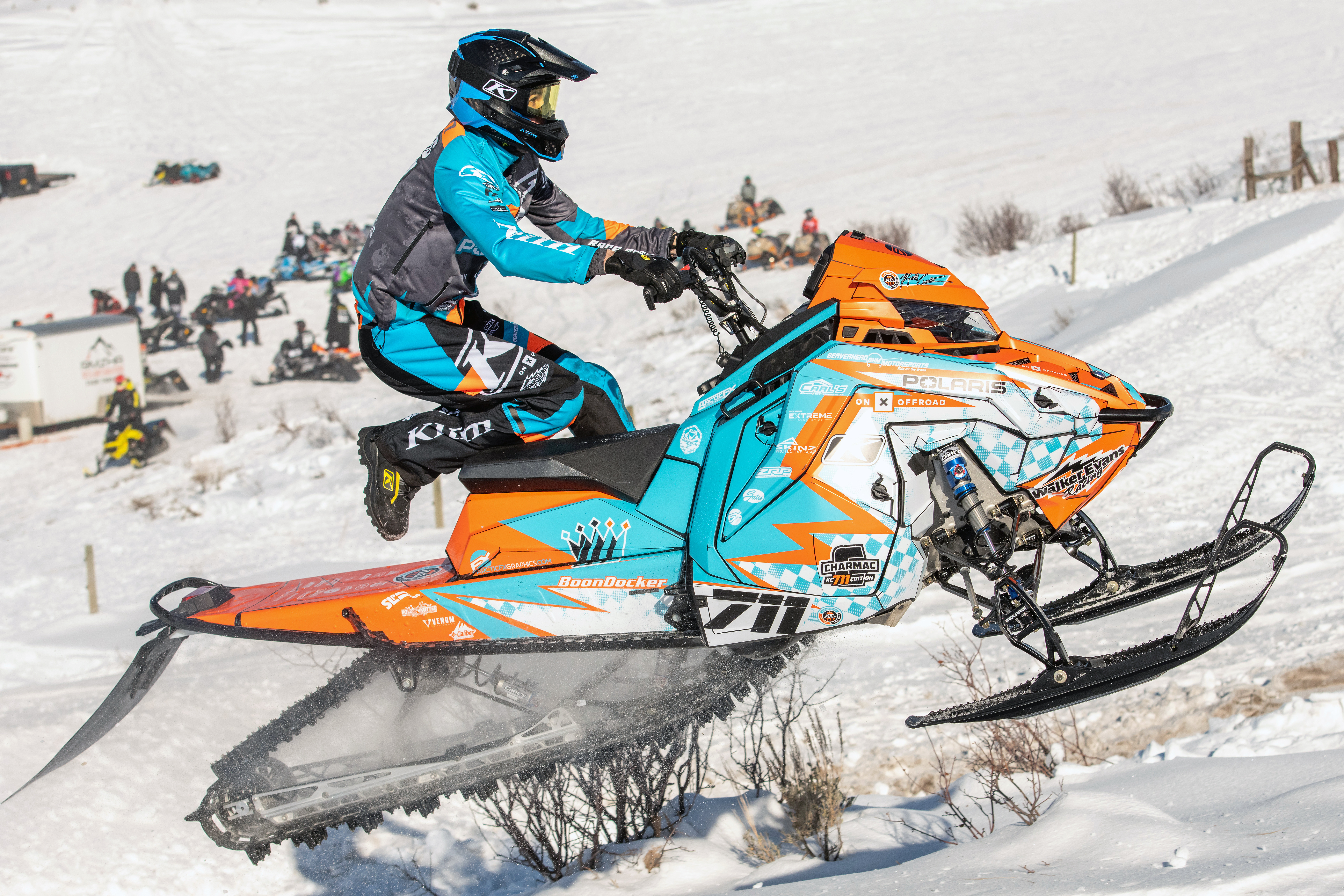 A Polaris Matryx Mountain snowmobile with a orange, blue and white KC711 Ignition custom vinyl wrap.