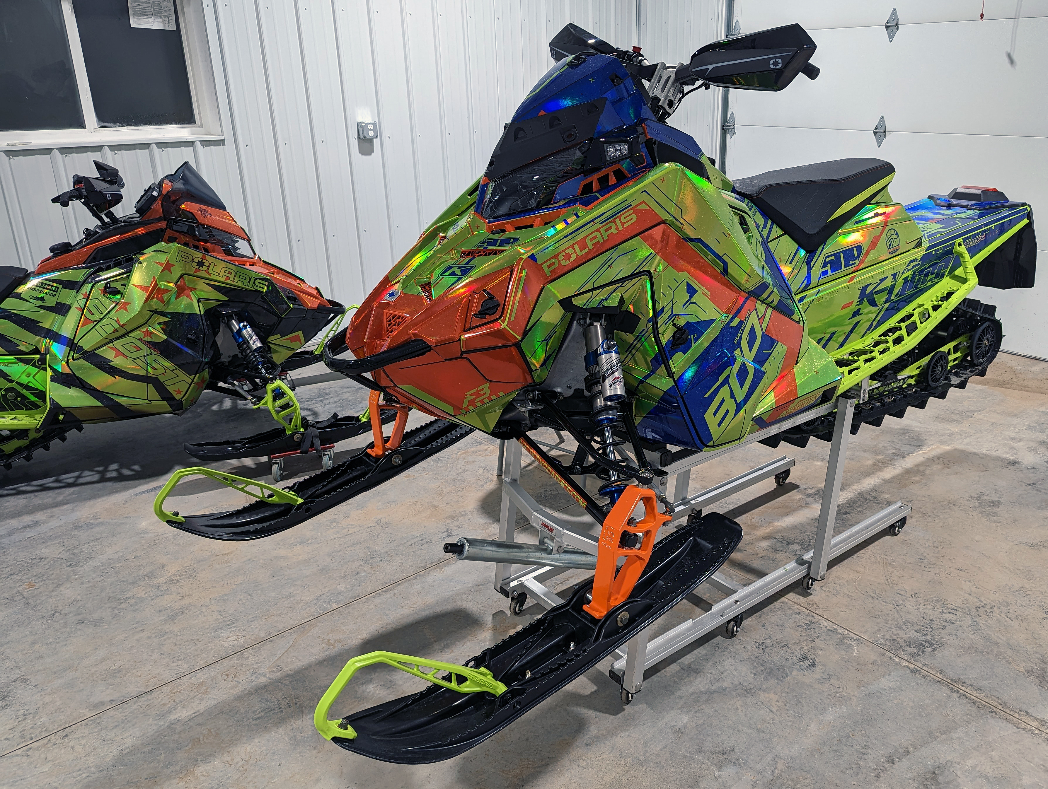 A Polaris Matryx Mountain snowmobile with a chrome, lime squeeze, blue, and orange Klim Recoil custom vinyl wrap.