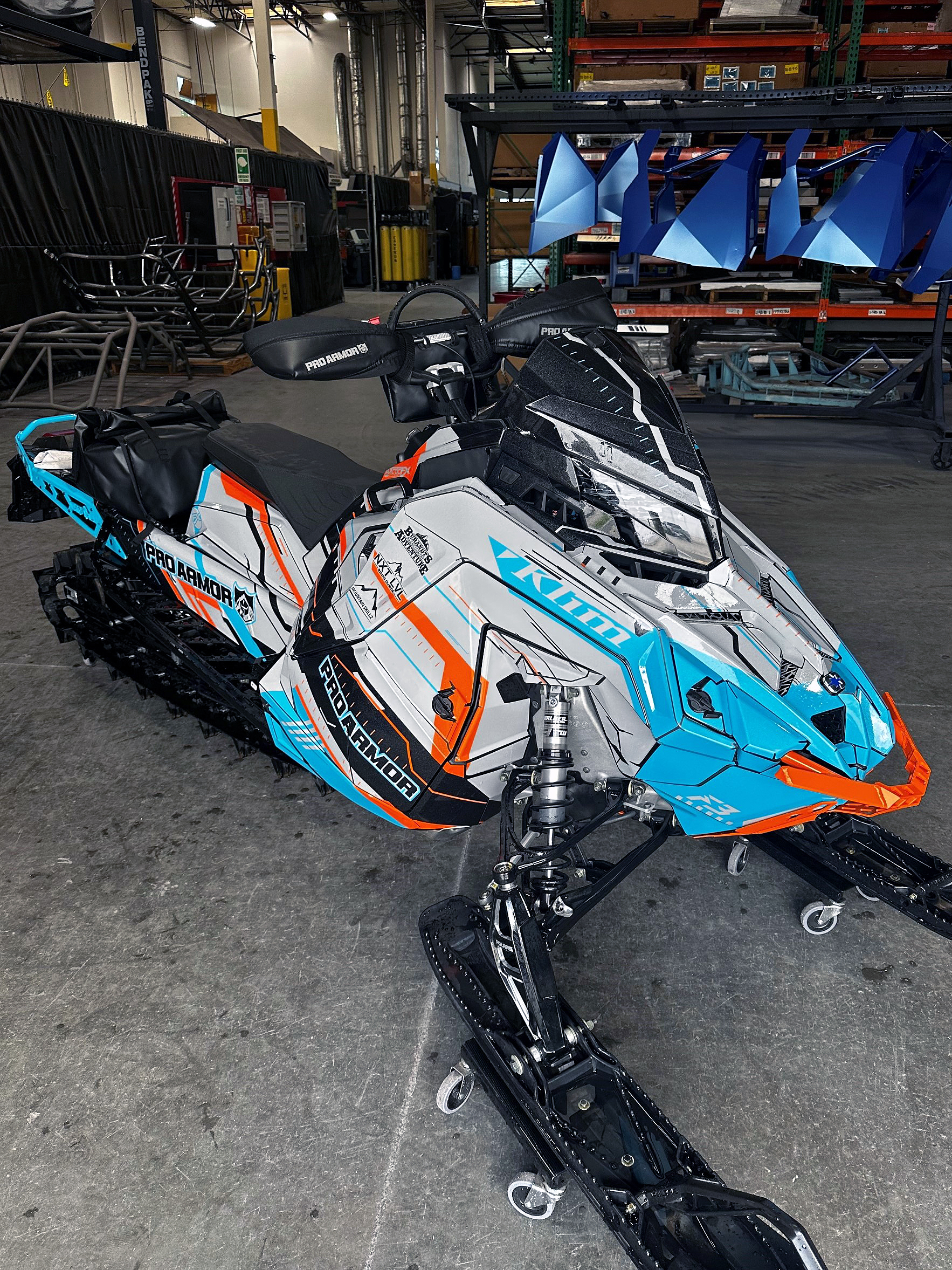 A Polaris Matryx Mountain snowmobile with a white, blue, and orange Klim Recoil custom vinyl wrap.