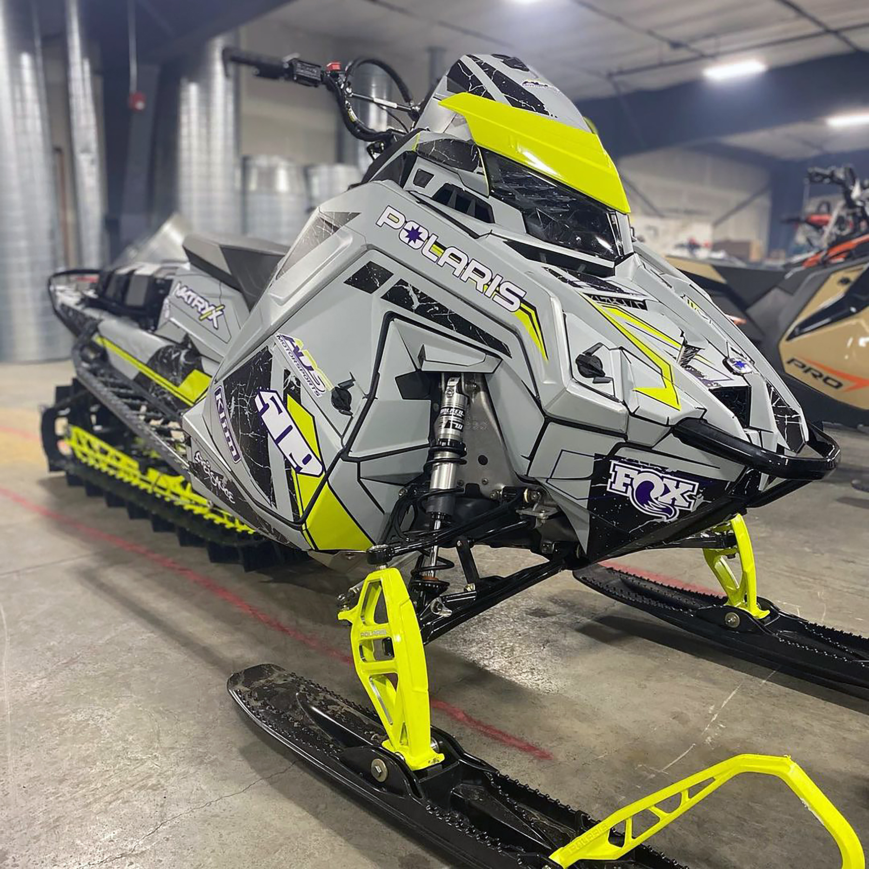 A Polaris Matryx Mountain snowmobile with a lime squeeze, gray and black Rogue custom vinyl wrap.