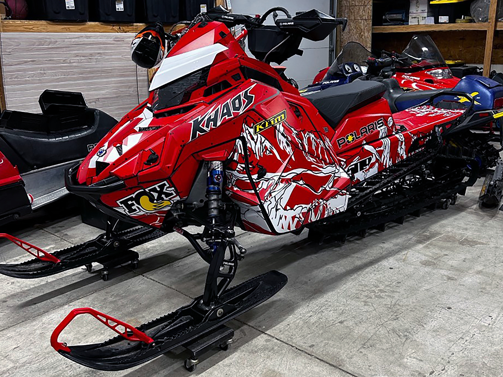 A Polaris Matryx Mountain snowmobile with a red, white, and black Sherman AK Assault custom vinyl wrap.