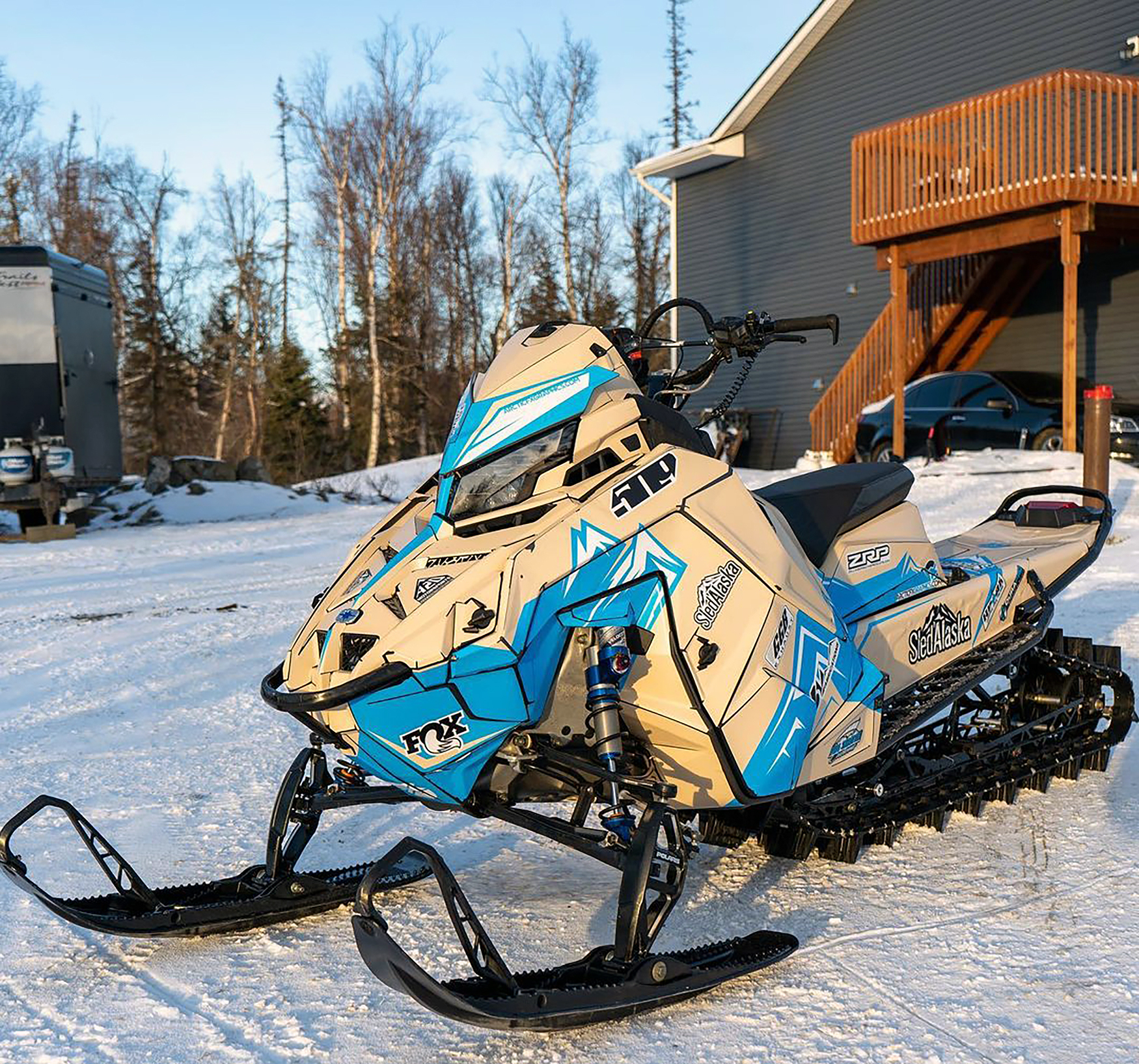 A Polaris Matryx Mountain snowmobile with a beige, blue, and white Teton custom vinyl wrap.