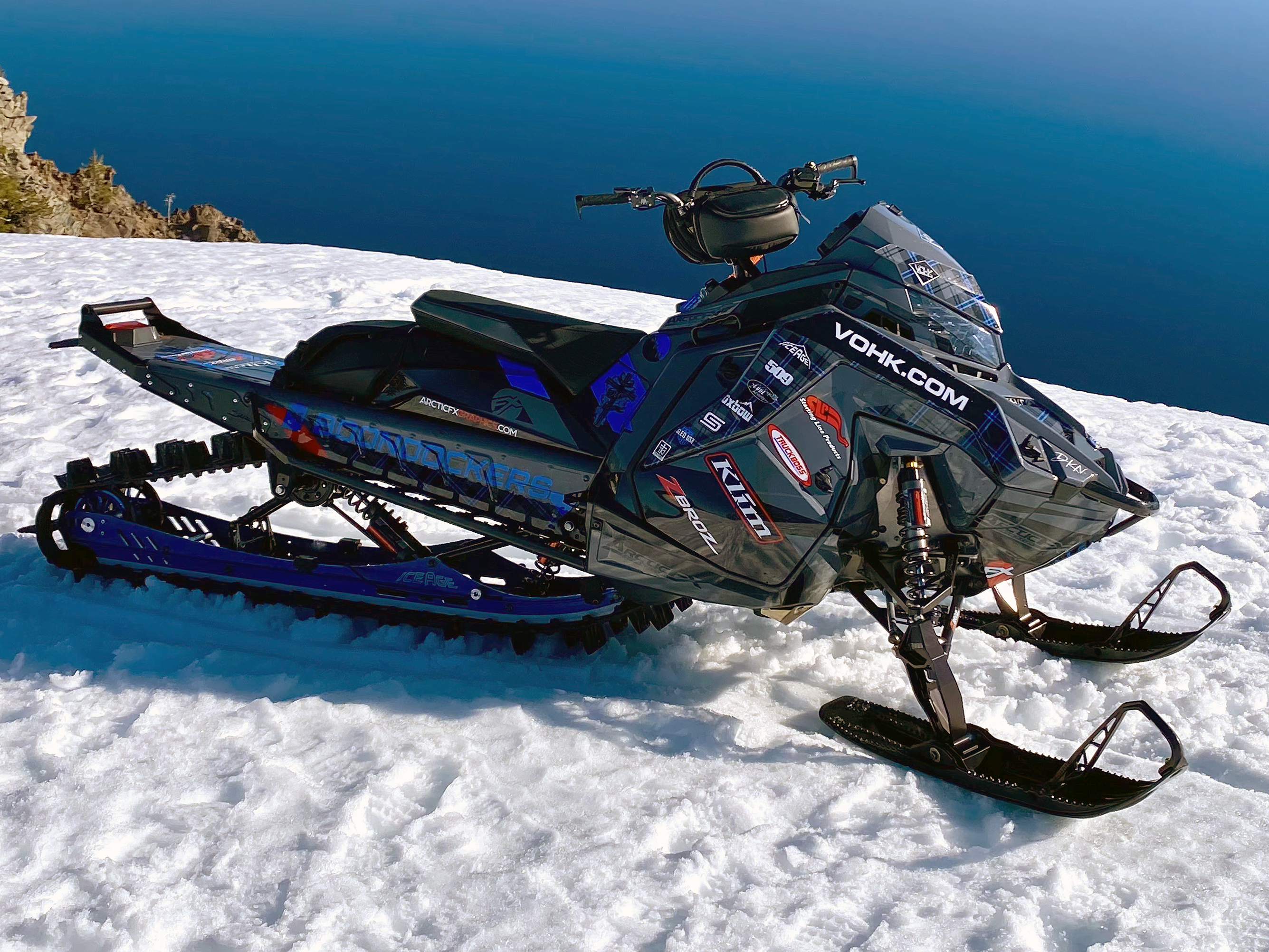 A Polaris Matryx Mountain snowmobile with a black, gray, and lime squeeze Yukon custom vinyl wrap.