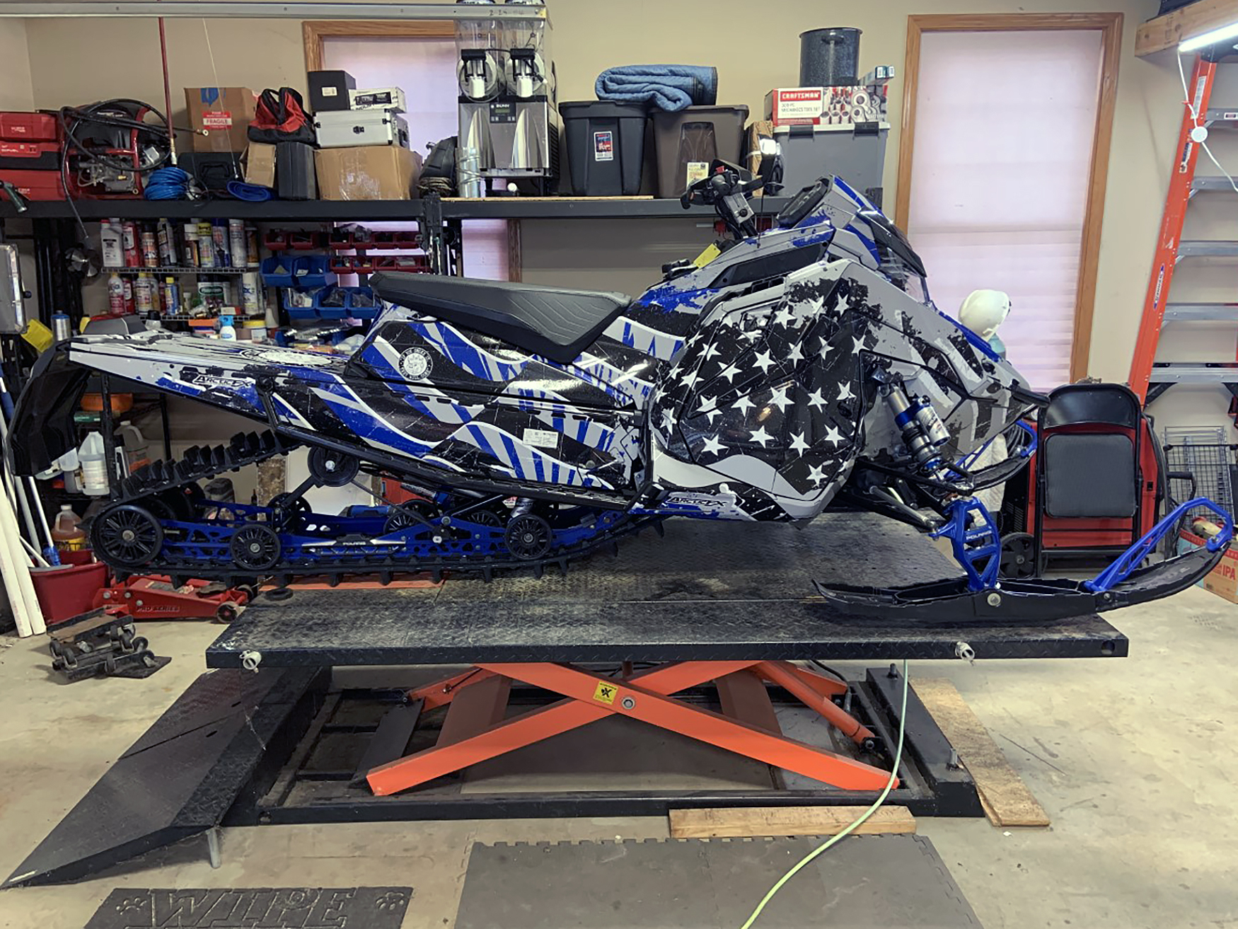 A Polaris Matryx Trail snowmobile with a gray, black, and blue grunge American Flag custom vinyl wrap.