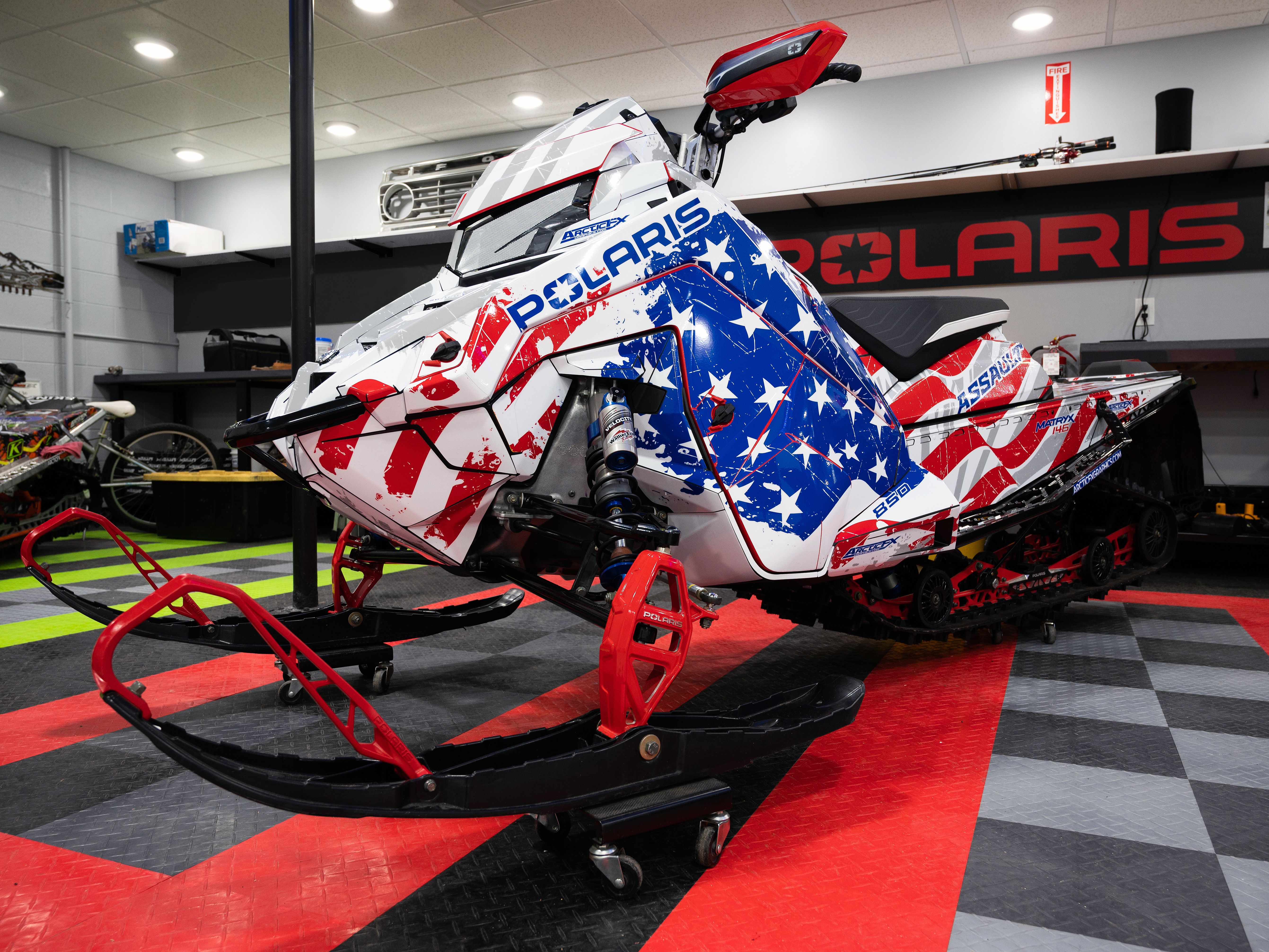 A Polaris Matryx Trail snowmobile with a red, white, and blue grunge American Flag custom vinyl wrap.
