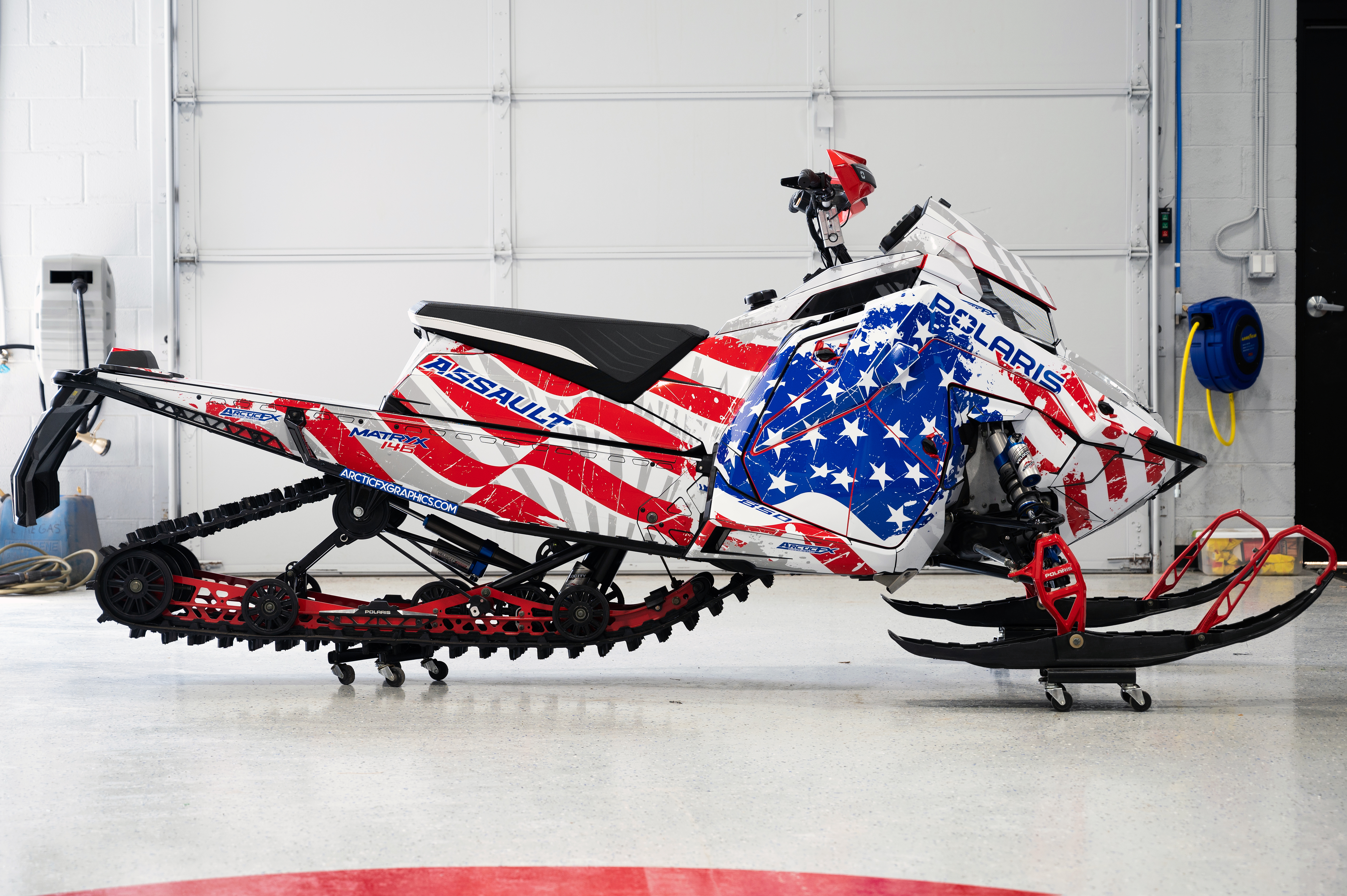 A Polaris Matryx Trail snowmobile with a red, white, and blue grunge American Flag custom vinyl wrap.