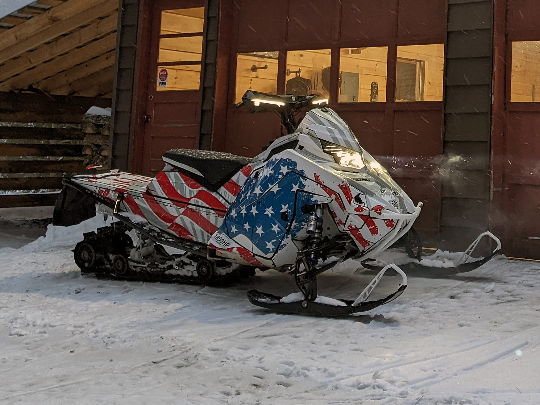 A Polaris Matryx Trail snowmobile with a red, white, and blue grunge American Flag custom vinyl wrap.