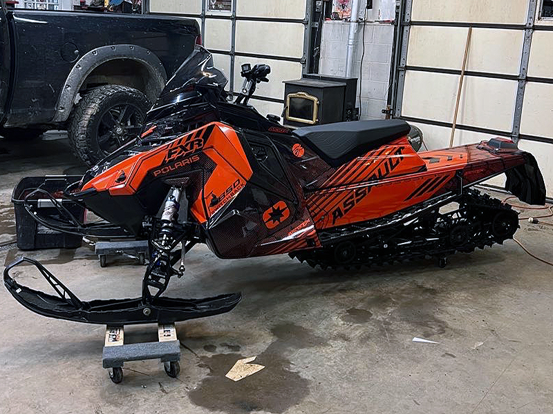 A Polaris Matryx Trail snowmobile with a orange and black Armada custom vinyl wrap.